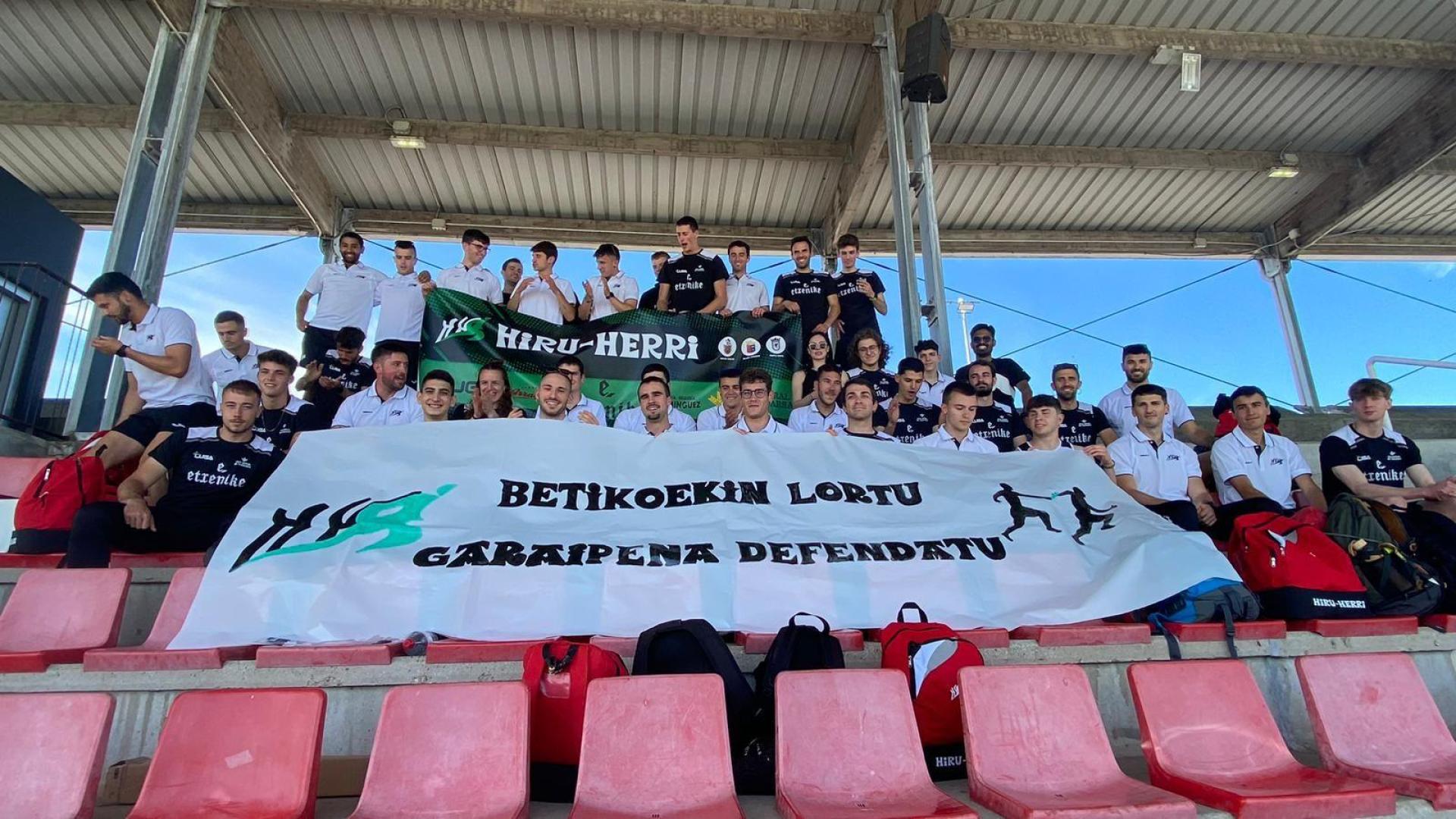 Los componentes de Hiru Herri posan con una pancarta de apoyo en la grada del estadio de Gijón