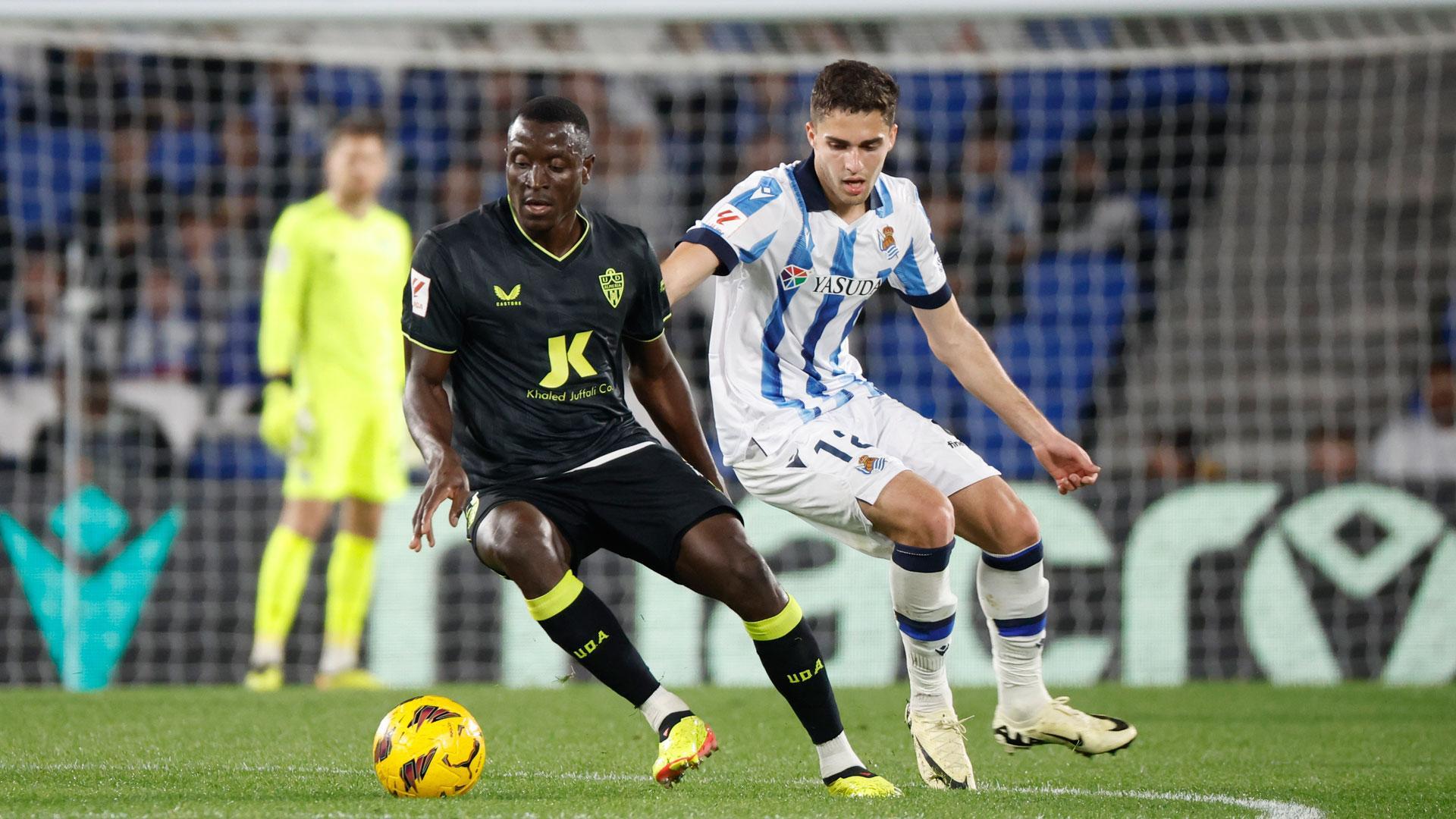El defensa senegalés del Almería, Dion Lopy (i), se lleva el balón ante el centrocampista ruso de la Real Sociedad, Arsen Zakharyan