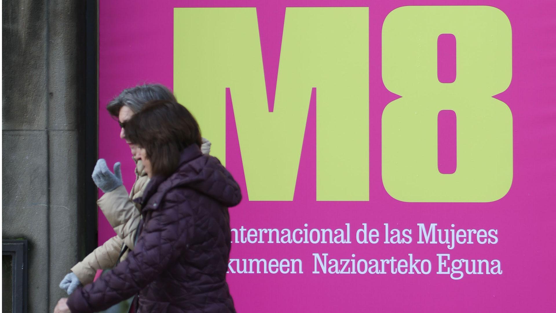 Dos personas pasan por delante de un cartel de la campaña lanzada con motivo del Día Internacional de la Mujer, habitual entre las acciones de sensibilización del Gobierno de Navarra