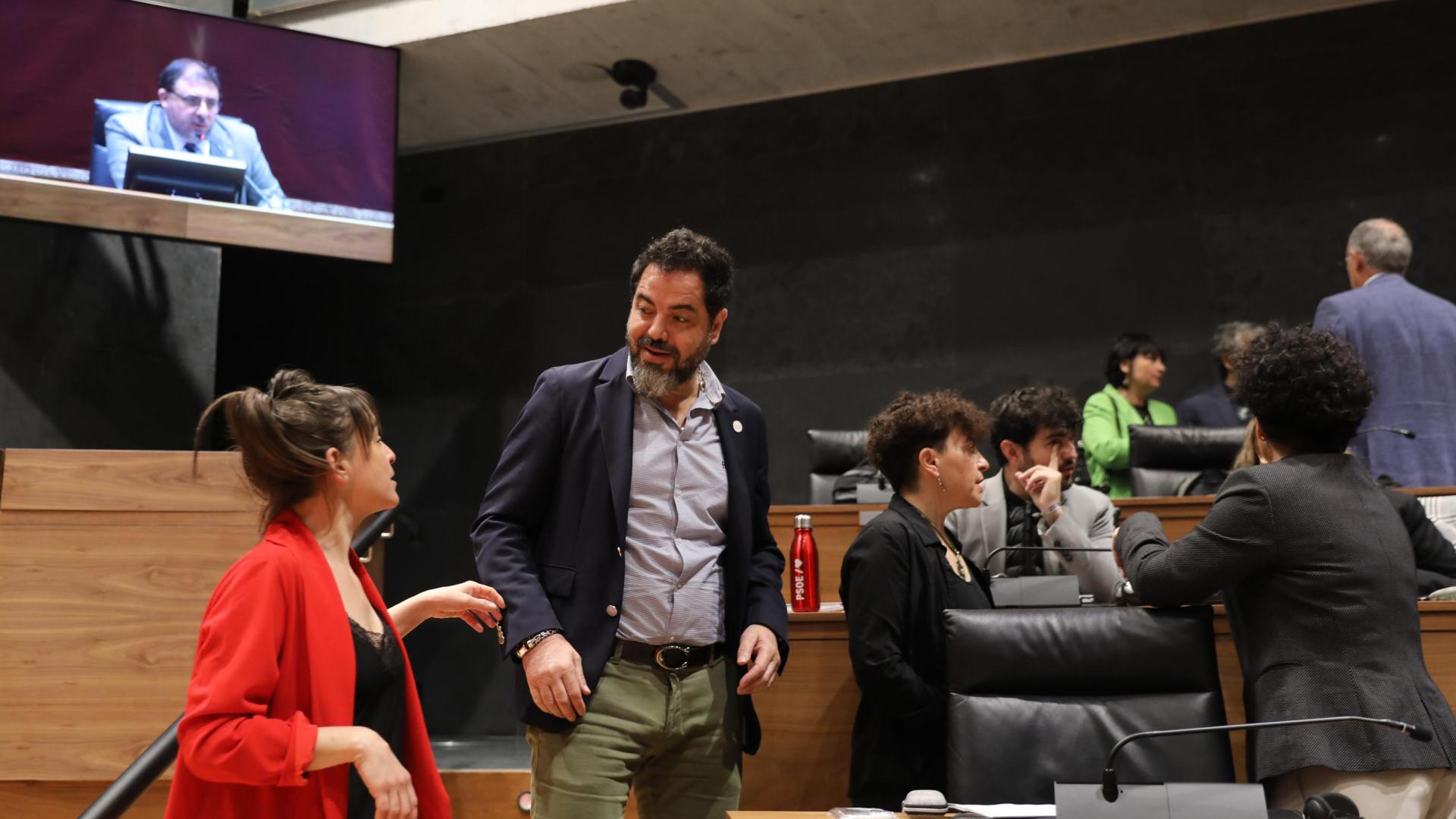 El secretario de organización del PSn, Ramón Alzórriz, conversa con la vicepresidenta Begoña Alfaro (Contigo). Arriba, a la derecha, los parlamentarios Adolfo Araiz y Laura Aznal (EH bildu)