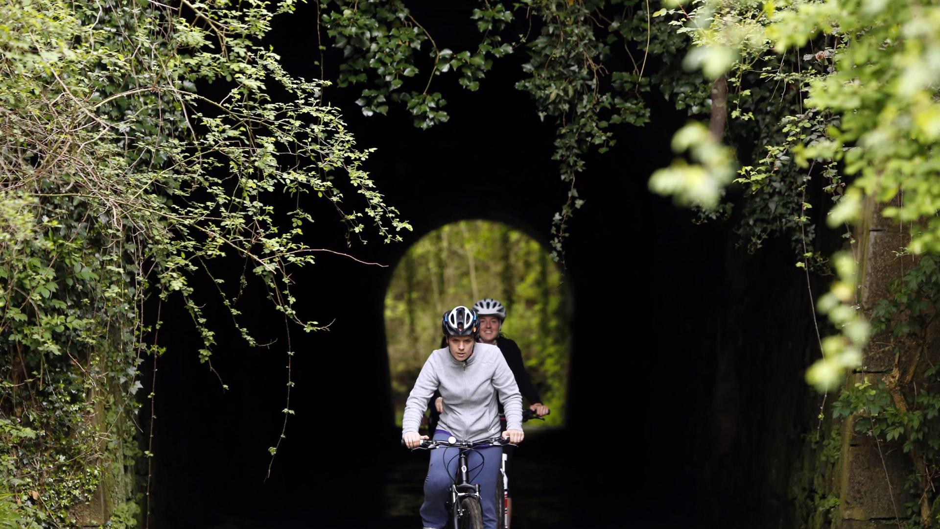 Dos cicloturistas atraviesan un túnel de la Vía Verde del Plazaola.