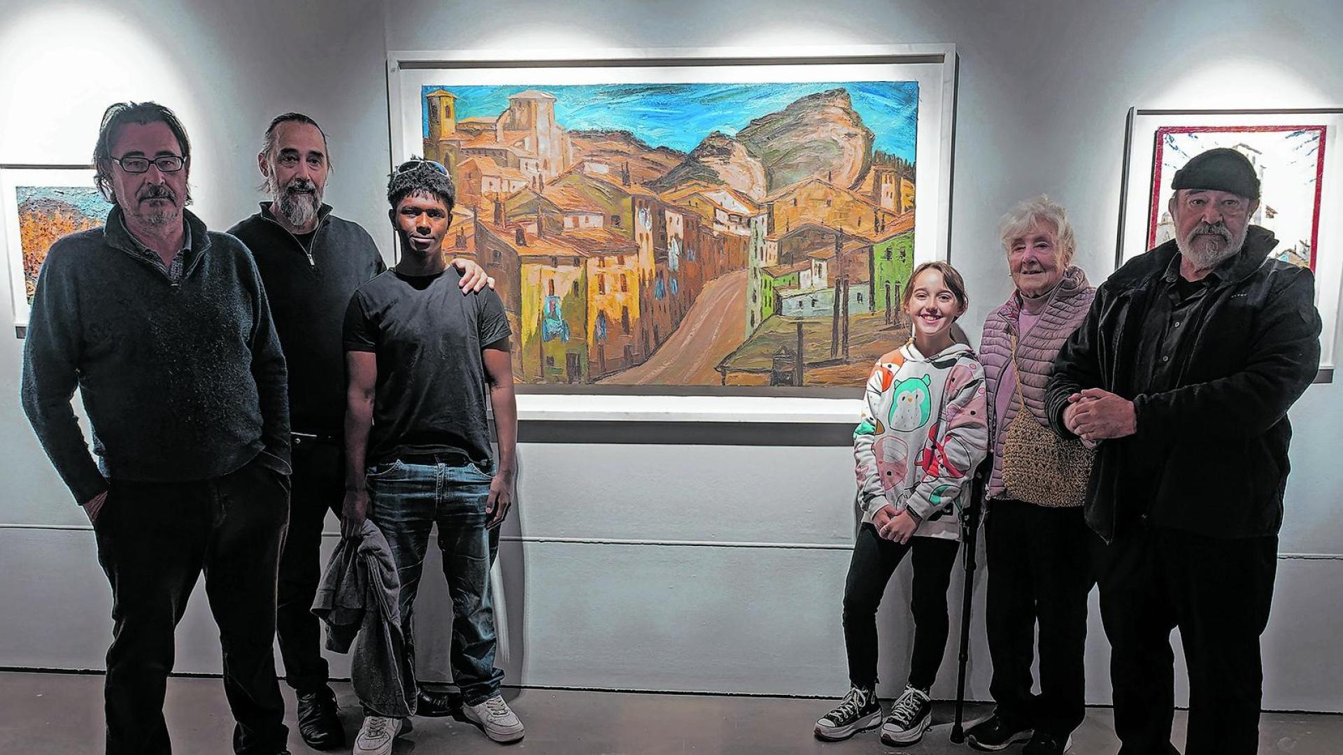 Carmen Lobo, viuda de Retana, con sus hijos y nietos ante una de las obras expuestas, con la calle Navarrería como elemento central.