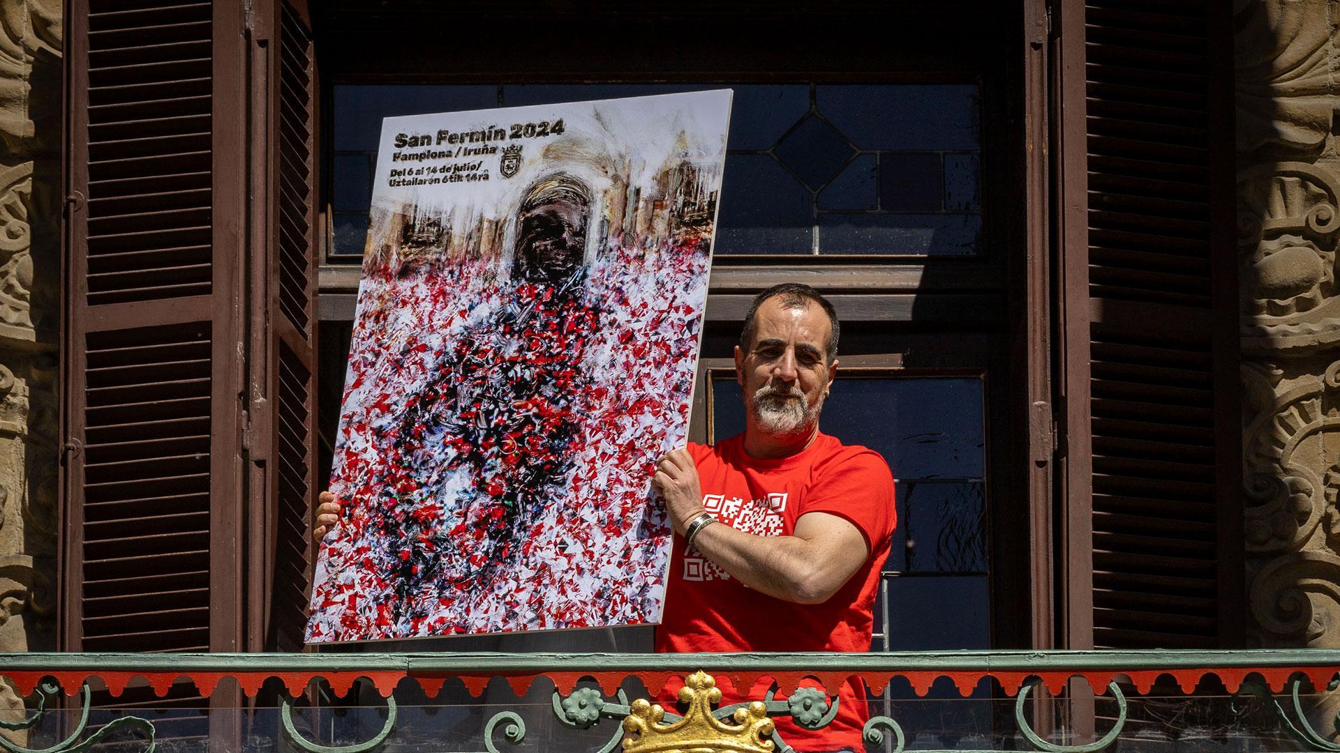 Ángel Blanco posa en el balcón del Ayuntamiento de Pamplona con su obra *Gaiteros", el cartel ganador que anunciará los Sanfermines 2024