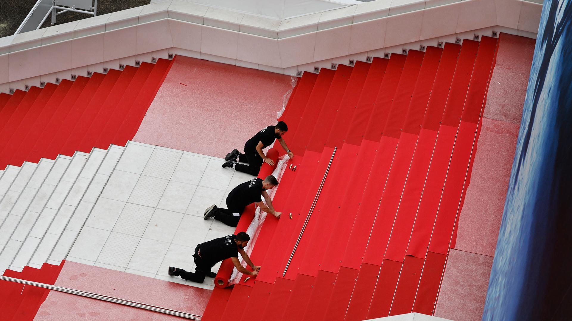 Trabajadores instalan la alfombra roja antes de la ceremonia de apertura del 77º Festival de Cine de Cannes