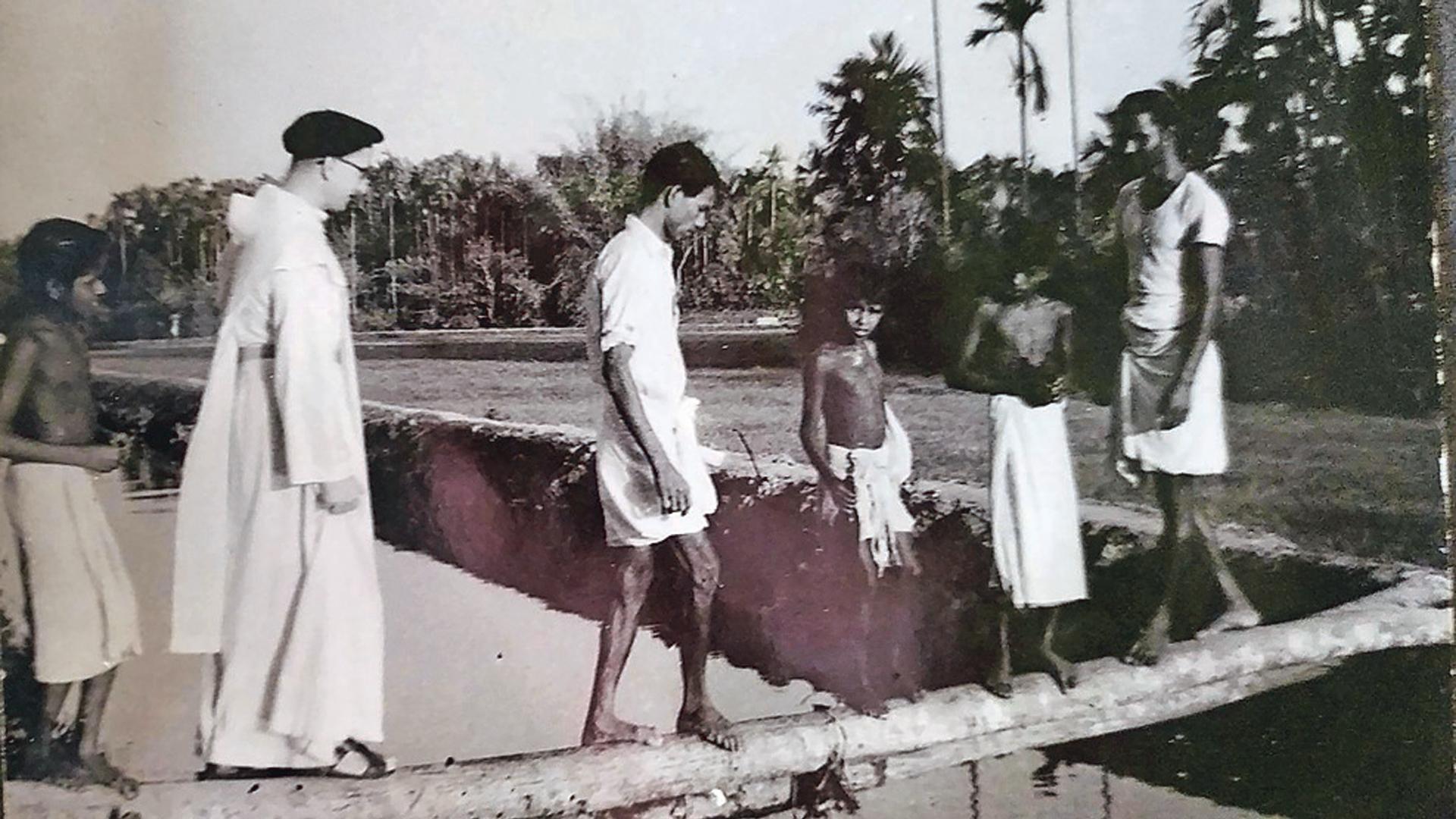 El padre Marcelino Iragui cruza un río junto a un grupo de jóvenes en la India