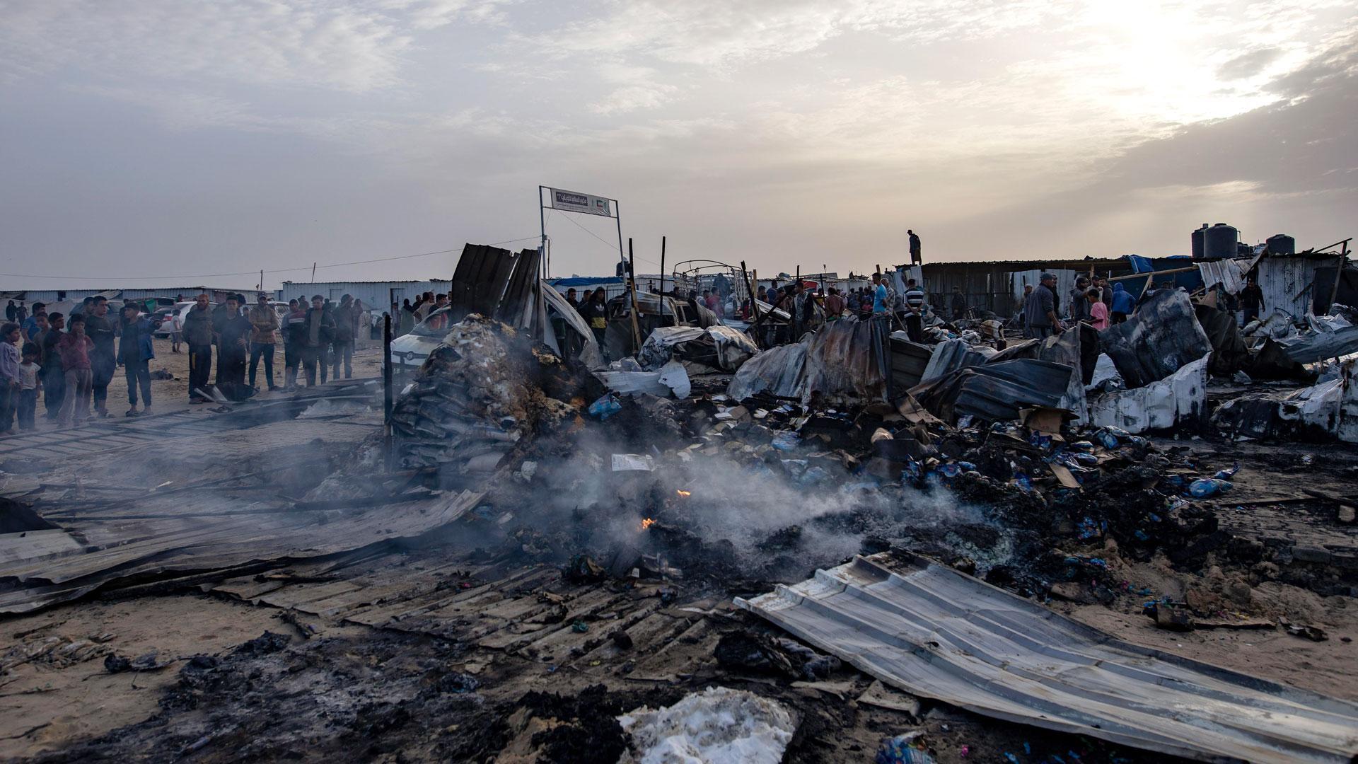 Los palestinos buscan entre los restos calcinados del campamento de desplazados en Rafah que ha sido atacado la pasada noche por el Ejército israelí y en el que han muerto 50 personas