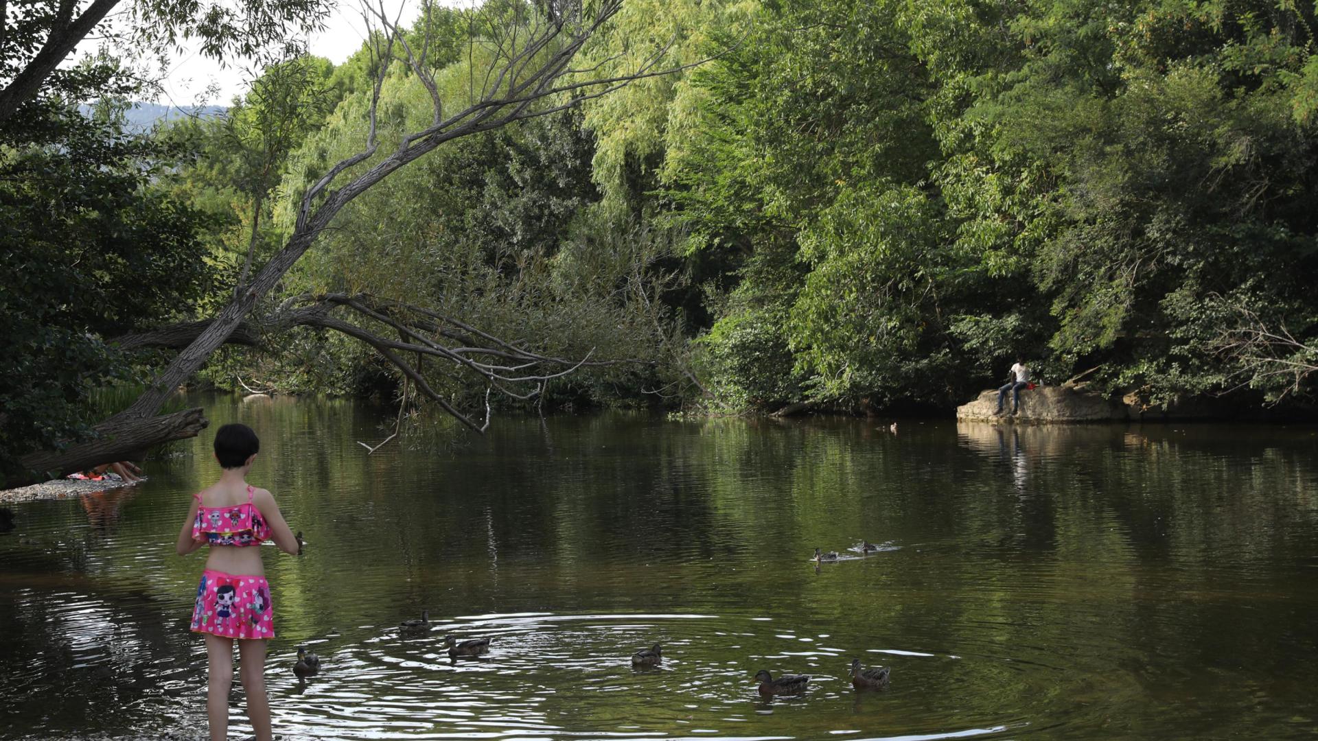 Una niña junto al río Arga a su paso por la Magdalena, en Pamplona.