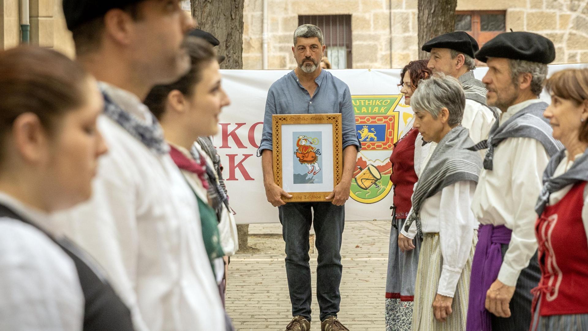 Fernando Hualde, con el galardón, frente a los dantzaris de Muthiko Alaiak.