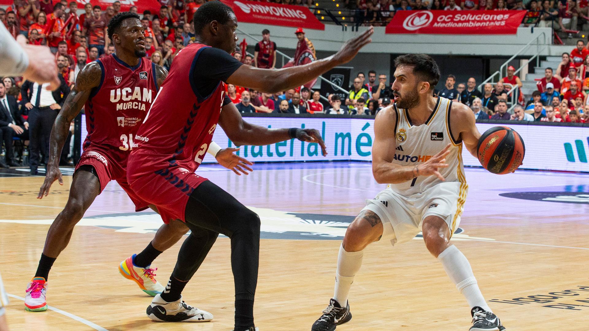El base argentino del Real Madrid Facundo Campazzo (d) controla el balón ante la presión del pívot senegalés de UCAM Murcia Moussa Diagne (c)