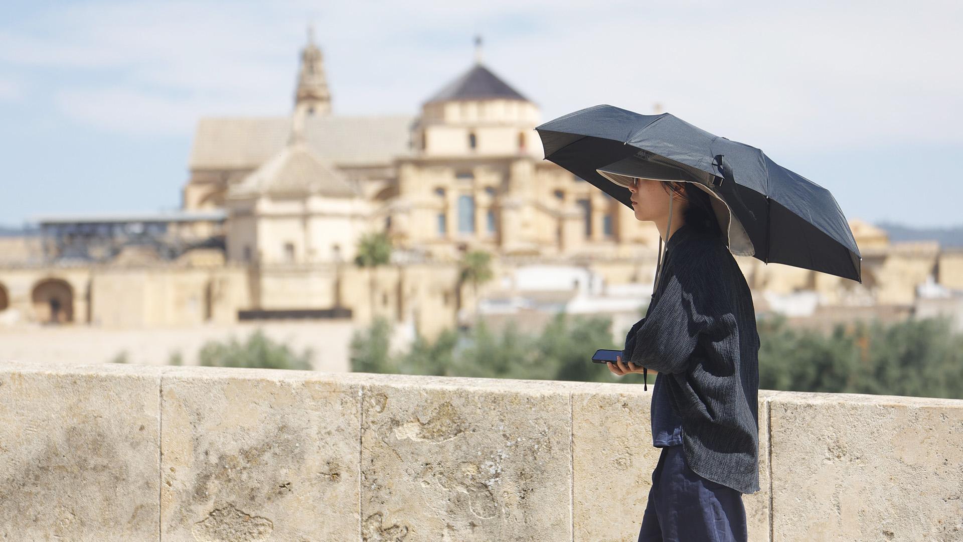 Una turista pasea por el Puente Romano con la Mezquita-Catedral al fondo en Córdoba