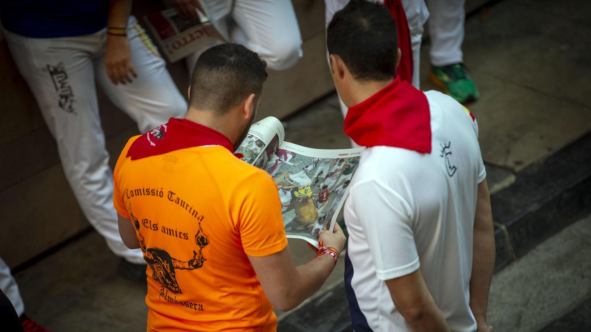 Dos corredores leen el periódico antes del encierro