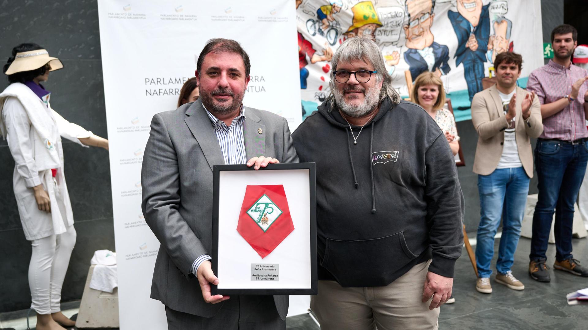 Carmelo Butini y Eider Bueno entregaron un pañuelo de la Peña Anaitasuna enmarcado al presidente del Parlamento, Unai Hualde, el último obsequio registrado en el Legislativo, con motivo de la exposición por el 75 aniversario de esa peña