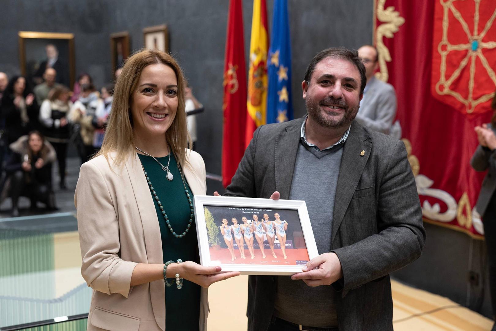 Enero de 2023, la entrenadora del Club de Gimnasia Rítmica de Ansoáin, Judith Fernández, entrega una foto de las ganadoras de la Medalla de Oro al presidente del Parlamento, Unai Hualde, en una recepción