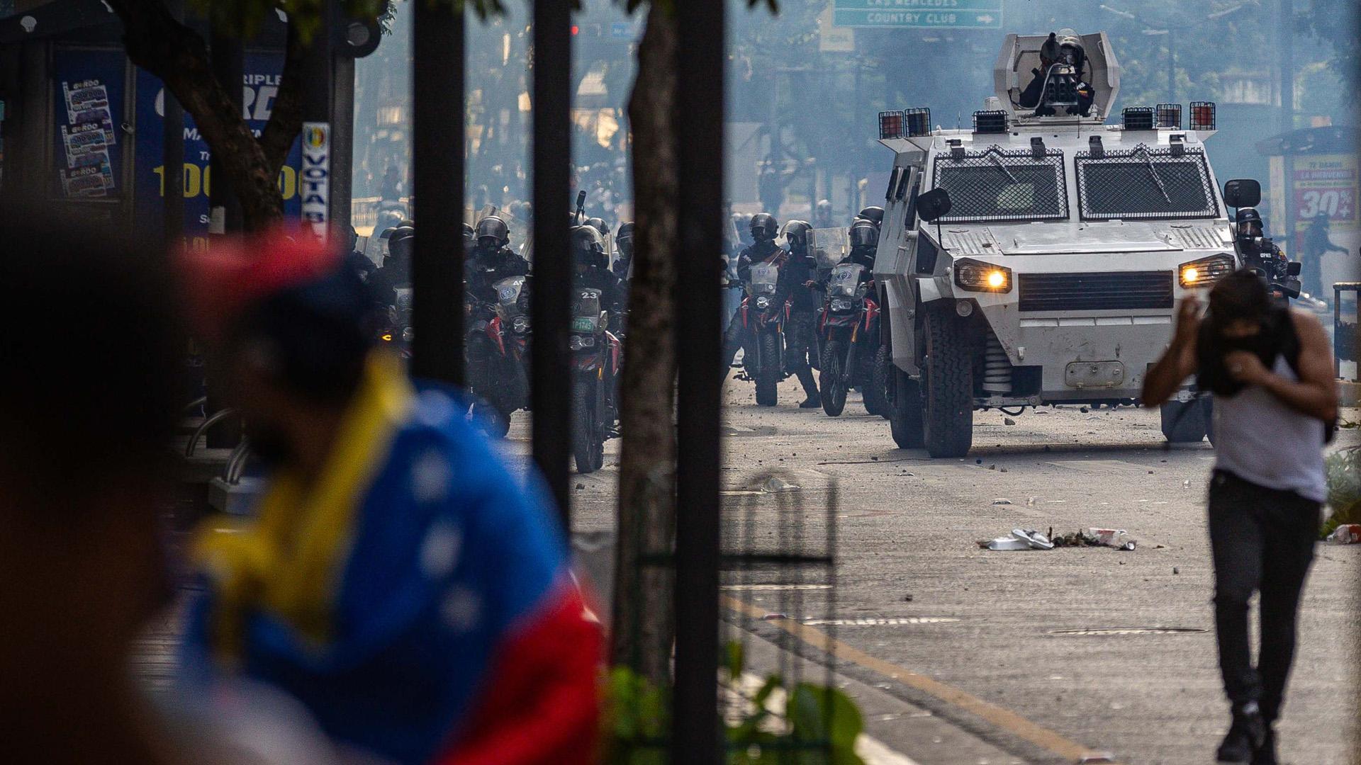 Manifestantes corren durante enfrentamientos entre opositores y miembros de la Guardia Nacional Bolivariana (GNB), por los resultados de las elecciones presidenciales este lunes, en Caracas