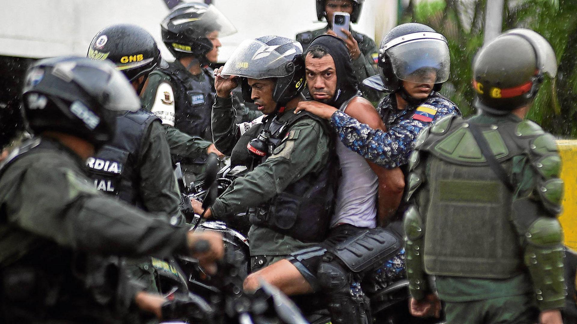 Agentes de la Guardia Nacional Bolivariana se llevan a un detenido en una manifestación en Caracas
