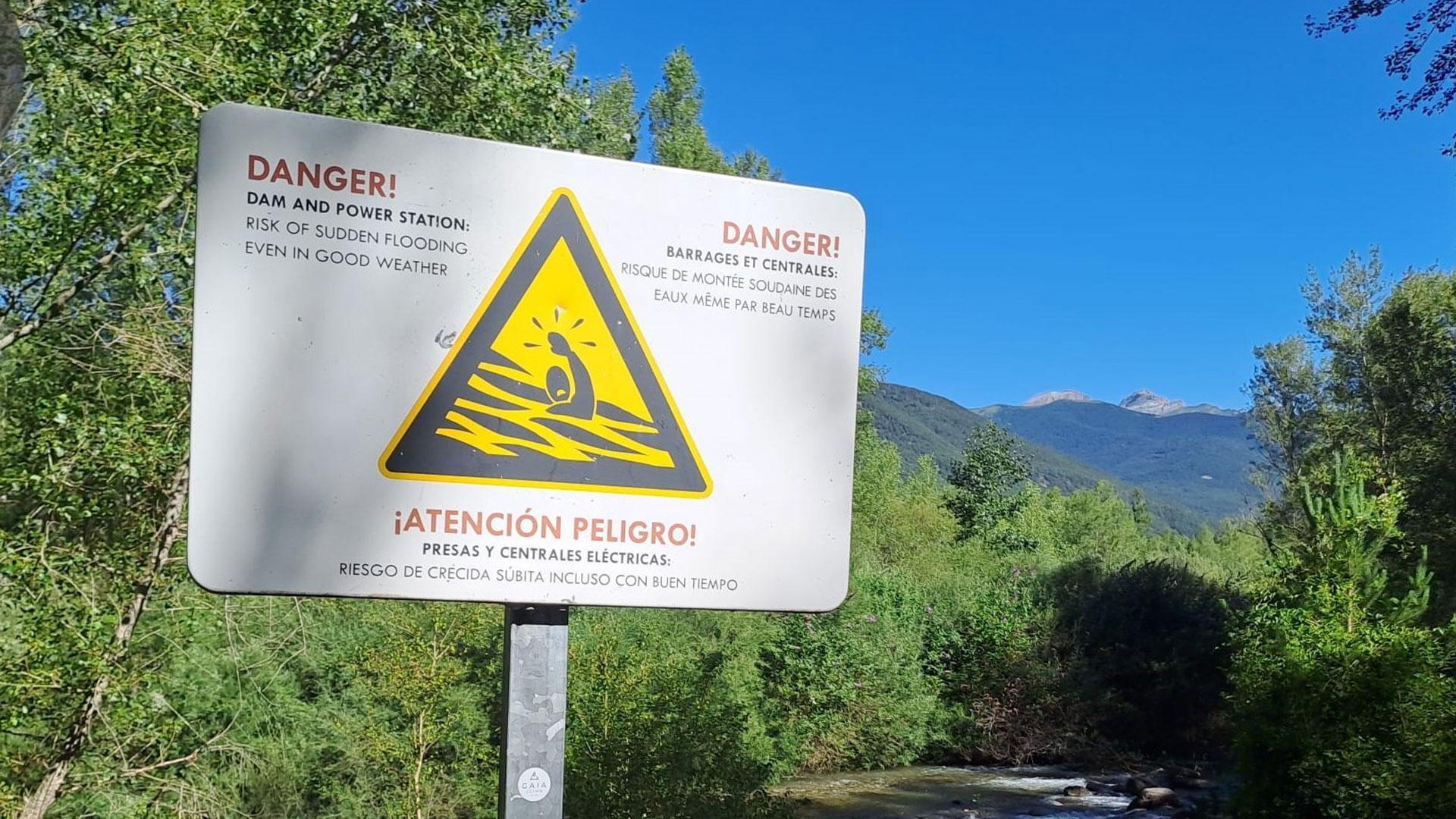 Cartel de peligro bañarse por el riesgo de crecida súbita del río porque estar cerca de una presa