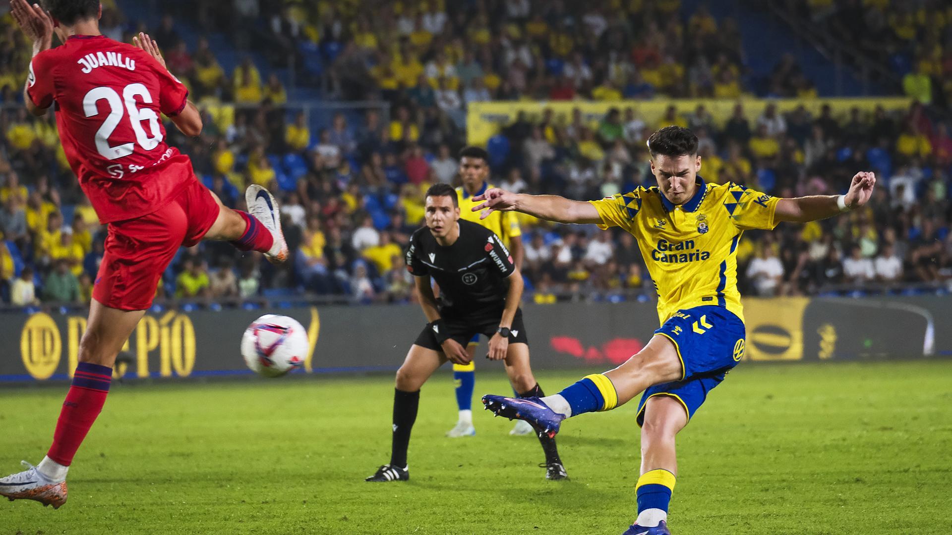 El jugador de la UD Las Palmas Mika Marmol dispara ante el defensa del Sevilla Juanlu