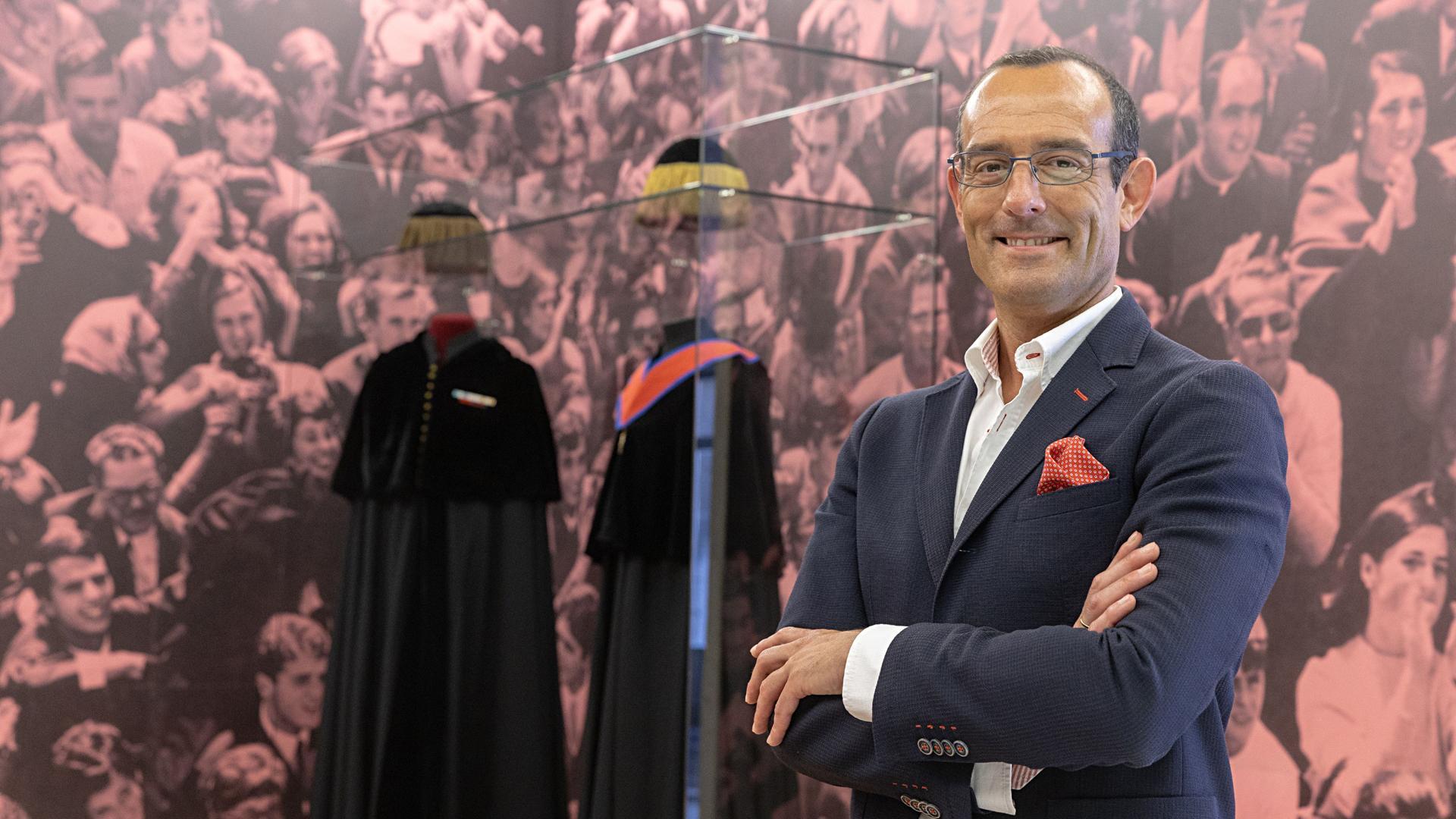 El investigador y coordinador general de la Asociación de Amigos de la Universidad de Navarra, Manuel Vilches, junto a las vestes académicas expuestas en el hall de Rectorado