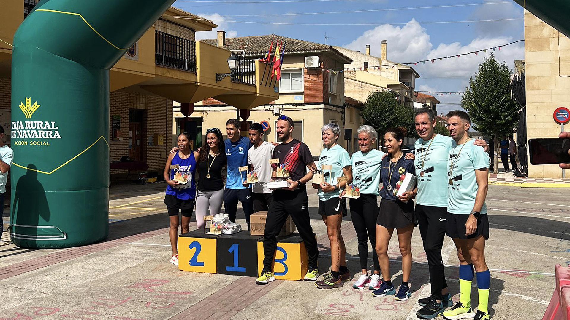 Podio con los ganadores en las categorías masculina y femenina y en las diferentes distancias posando con los trofeos en la línea de meta de la II Media Maratón Ruta del Barbo