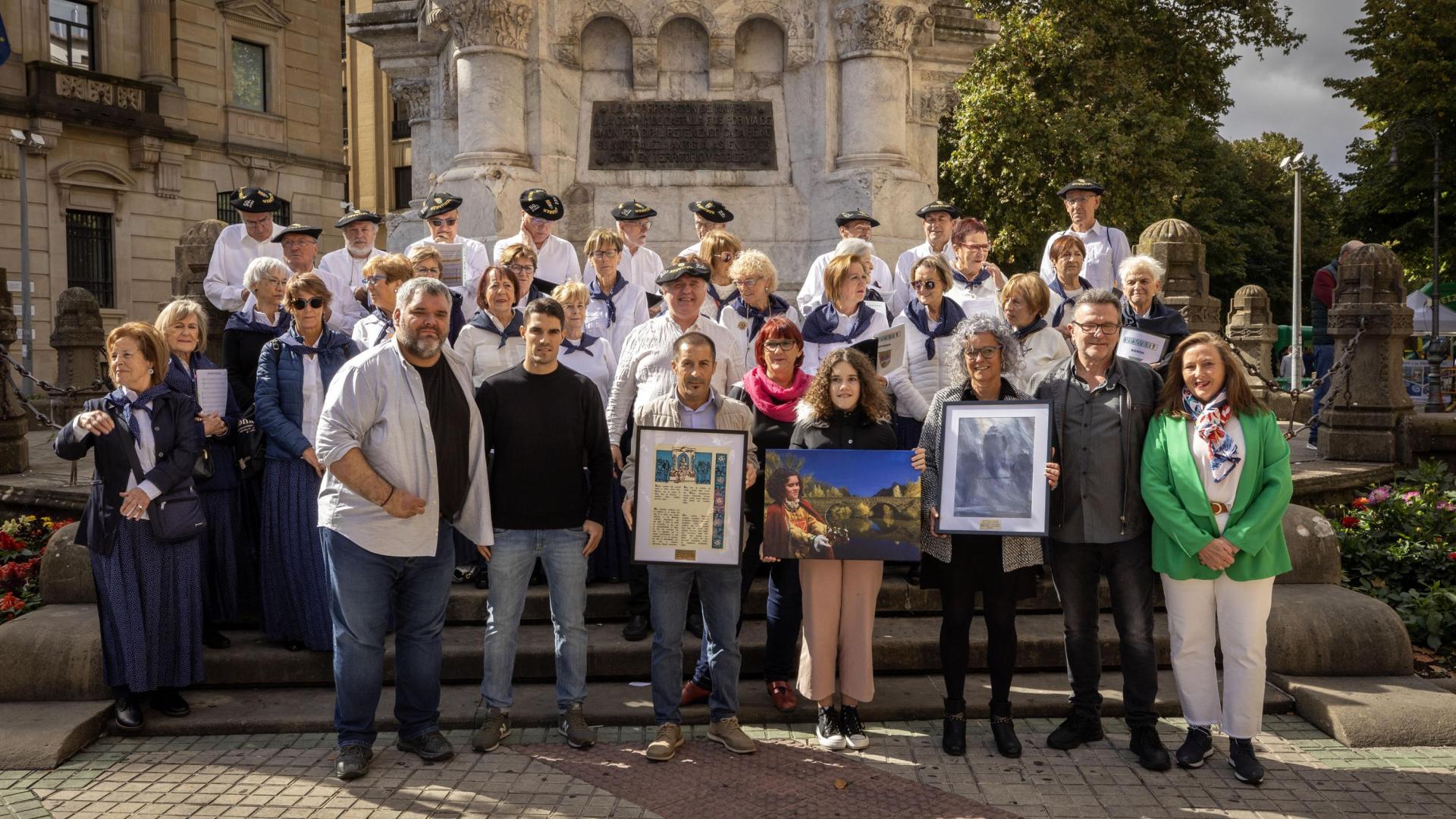 En el centro, el alcalde de Peralta, Juan Carlos Castillo; Zoe Vergara, reina de la Faba 2024 y la alcaldesa de Burlada, Berta Arizkun. Con ellos, el coro de Muthiko Alaiak y personas de la Junta de la peña.