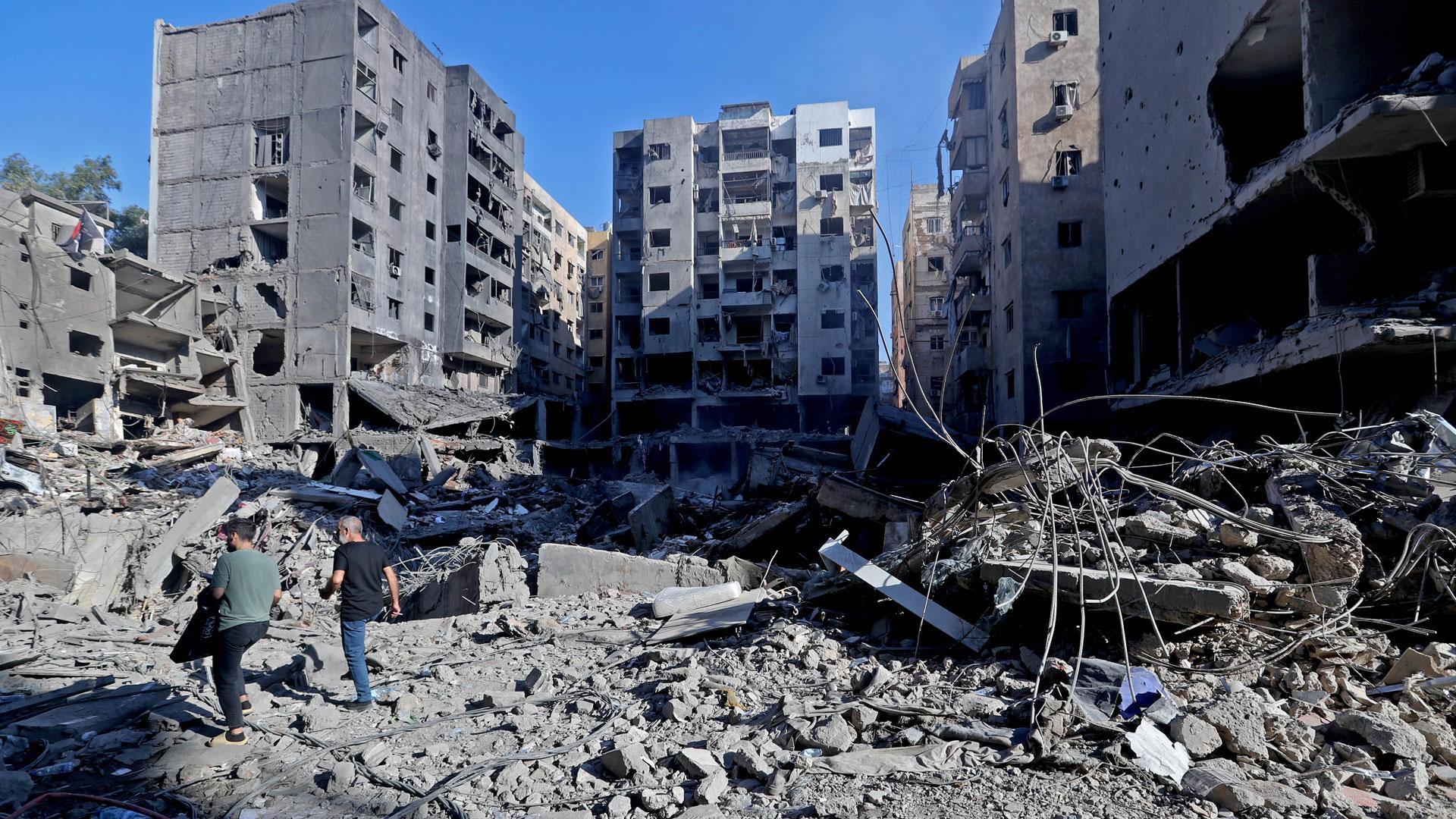 La gente camina entre los escombros de los edificios destruidos después de los ataques aéreos israelíes en el suburbio del sur de Beirut, Líbano, este domingo