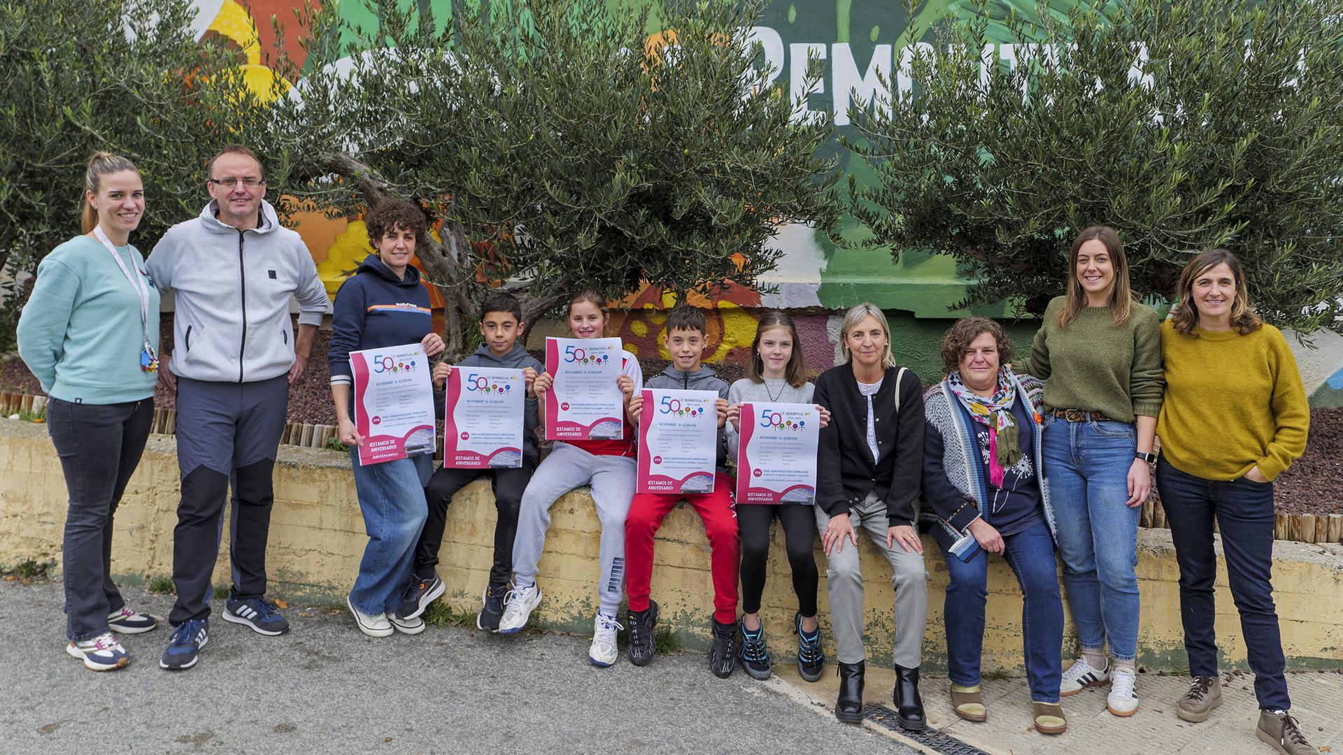 Desde la izda., Samantha Echarri Michelena, jefa de estudios de PAI; Unai Díez Cía, tutor en el modelo D; Izaro Puy Crespo, profesora de euskera; Eros Crespo Loján, alumno de 6º de Primaria de PAI; Iranzu Vidán Yanci, alumna de 6º de PAI; Aiur Nuin Olite, alumno de 6º de modelo D; Laia Garro Mínguez, alumna de 6º en modelo D; Piluca Ochoa Azcona, logopeda del centro; Enkarni Valencia García, tutora en modelo D; Elena Jiménez Herce, tutora en PAI; y Amaia Arbizu Calanda, jefa de estudios del modelo D con los carteles de la fiesta del 50 aniversario