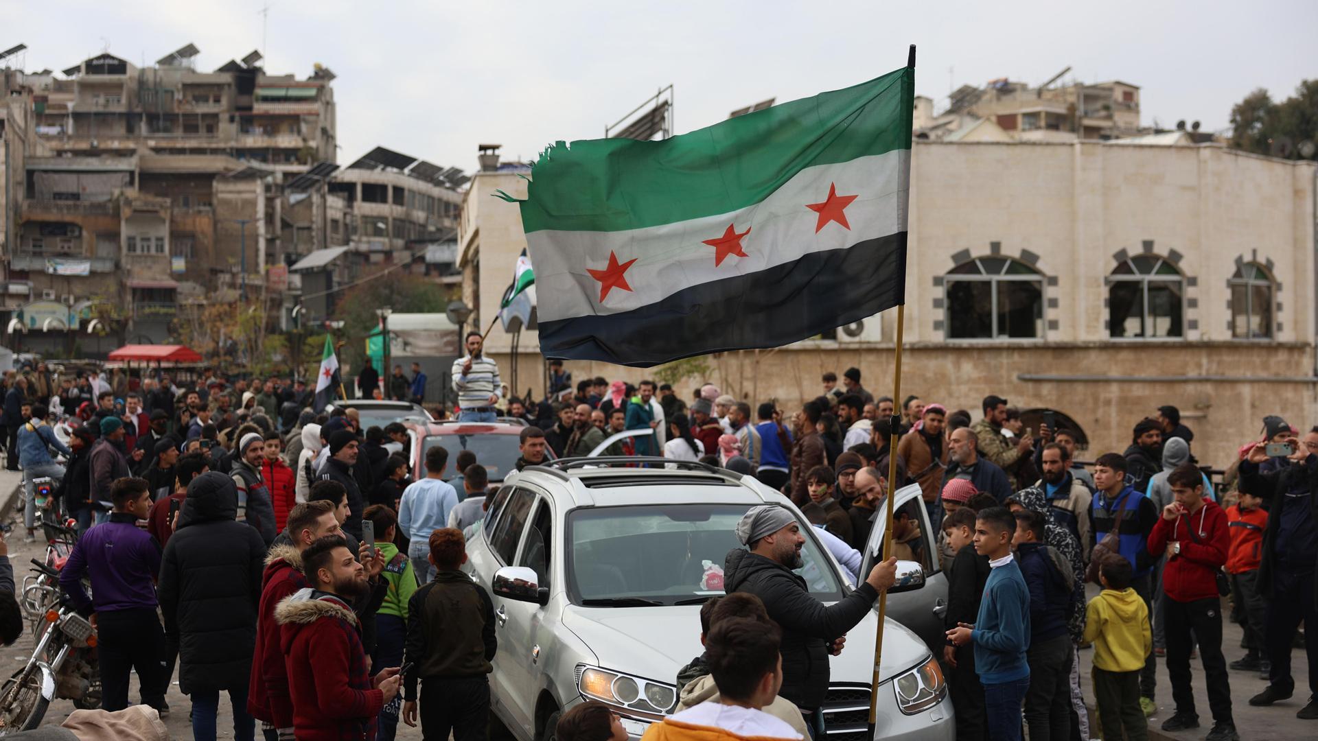 Una persona ondea una bandera de la oposición siria después de que los combatientes de la oposición tomaran el control de la ciudad de Hama