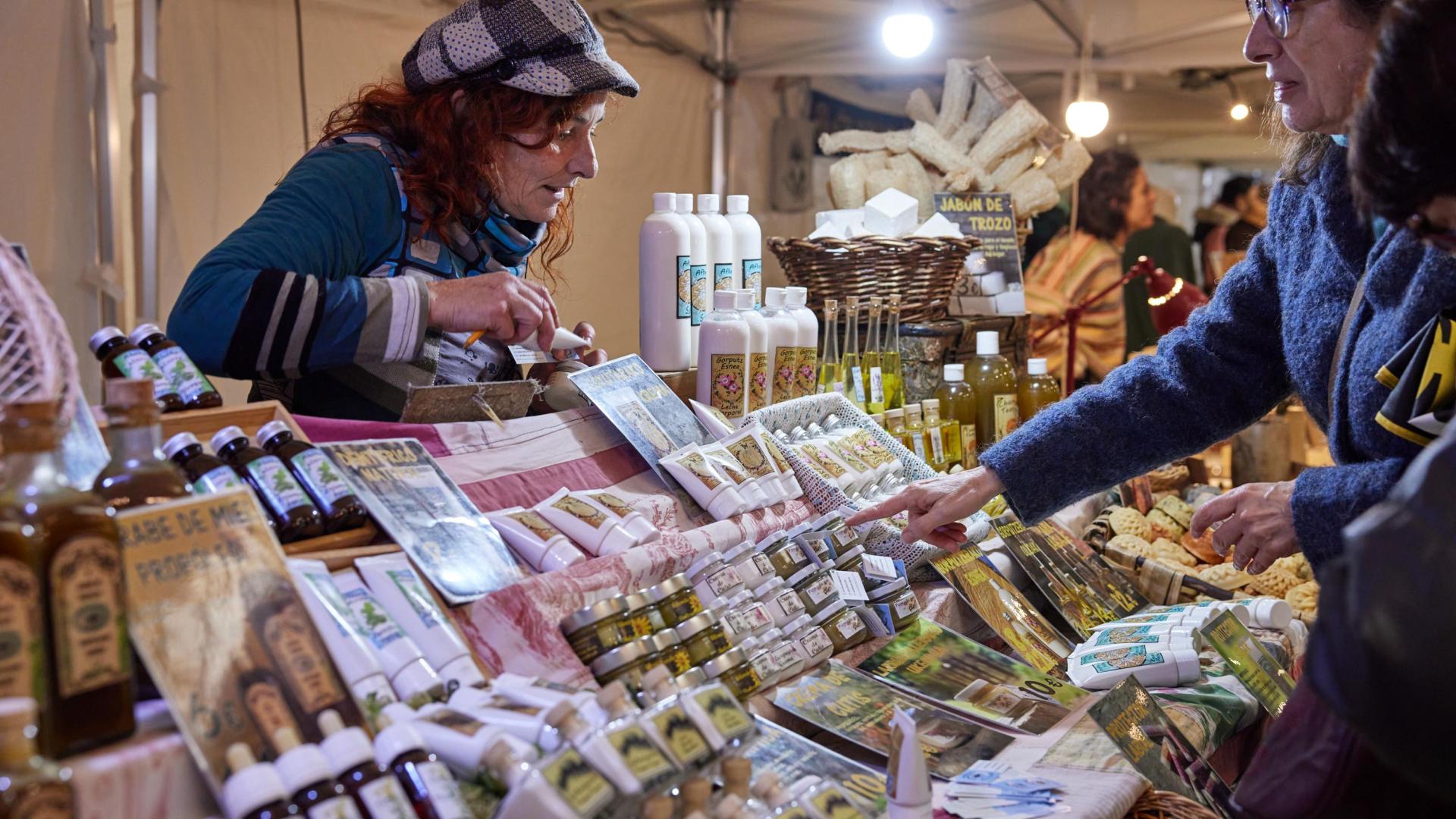 Una vendedora se interesa por productos de cosmética natural en el mercado de artesanía organizado por Geltoki.