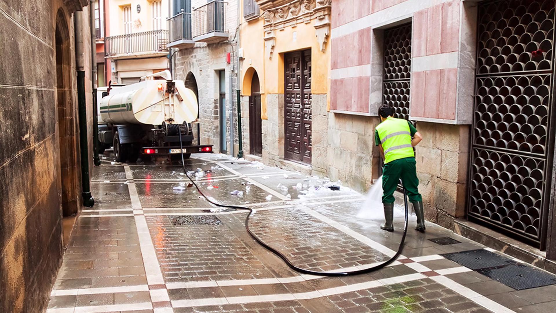 Un empleado municipal pasa la manguera en una calle del Casco Viejo de Pamplona /