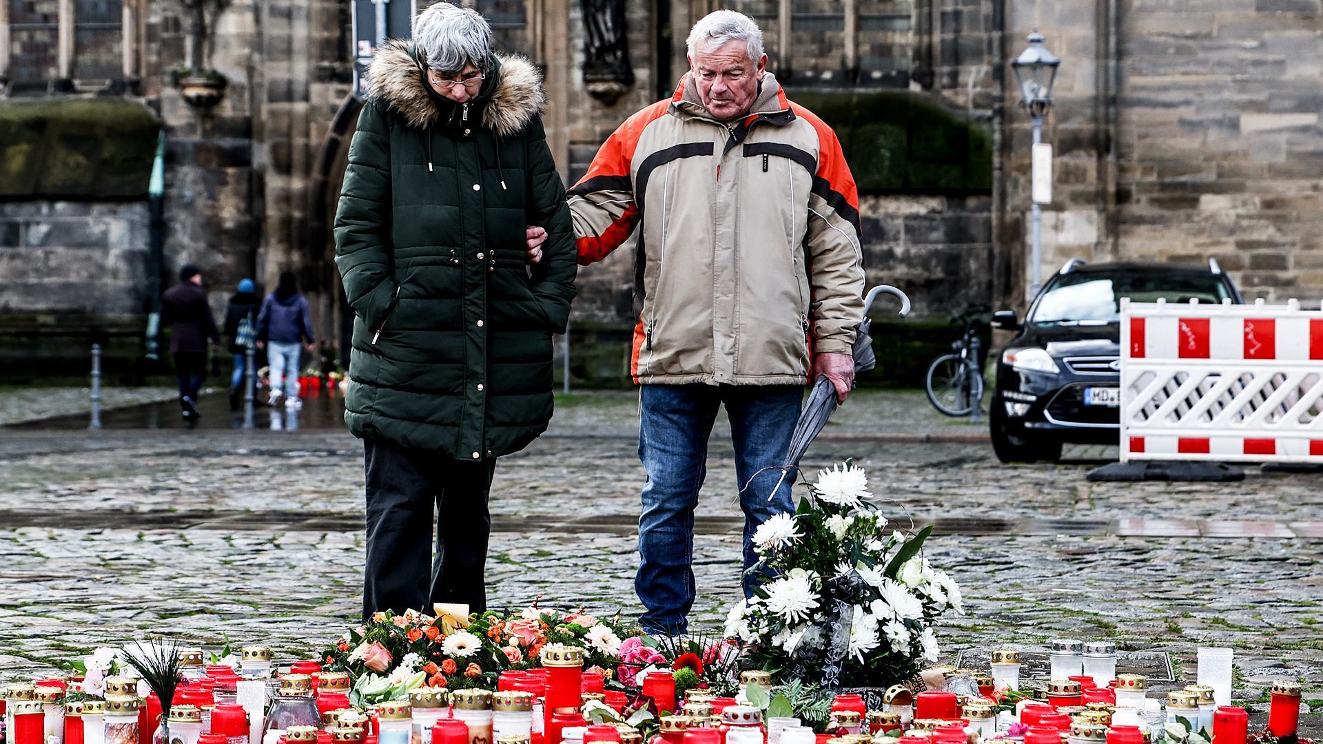 Dos personas contemplan los objetos dejados en el lugar del accidente, ante la catedral de Magdeburgo /