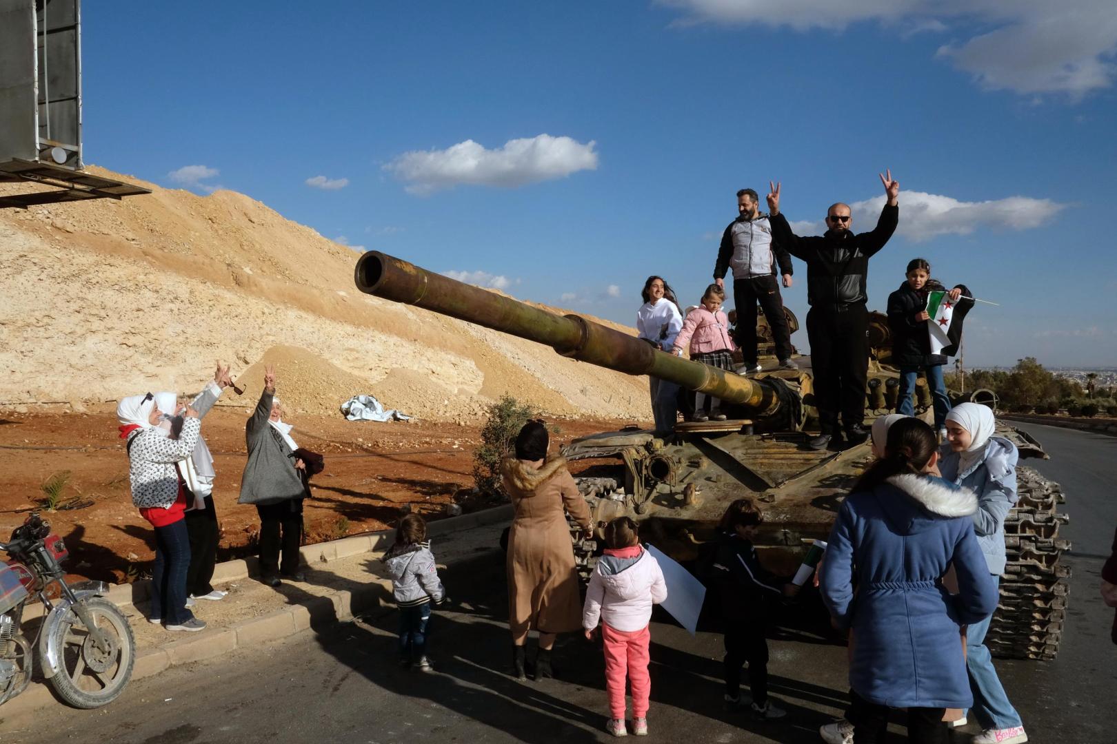Una familia celebra la caída del régimen en un tanque abandonado en Damasco.