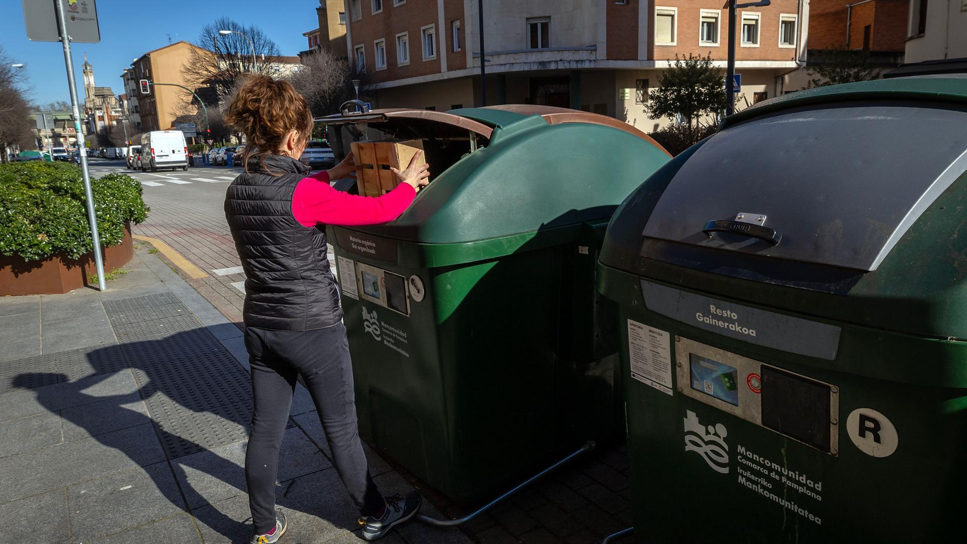Una mujer deposita residuos en un contenedor de la calle Olite de Pamplona