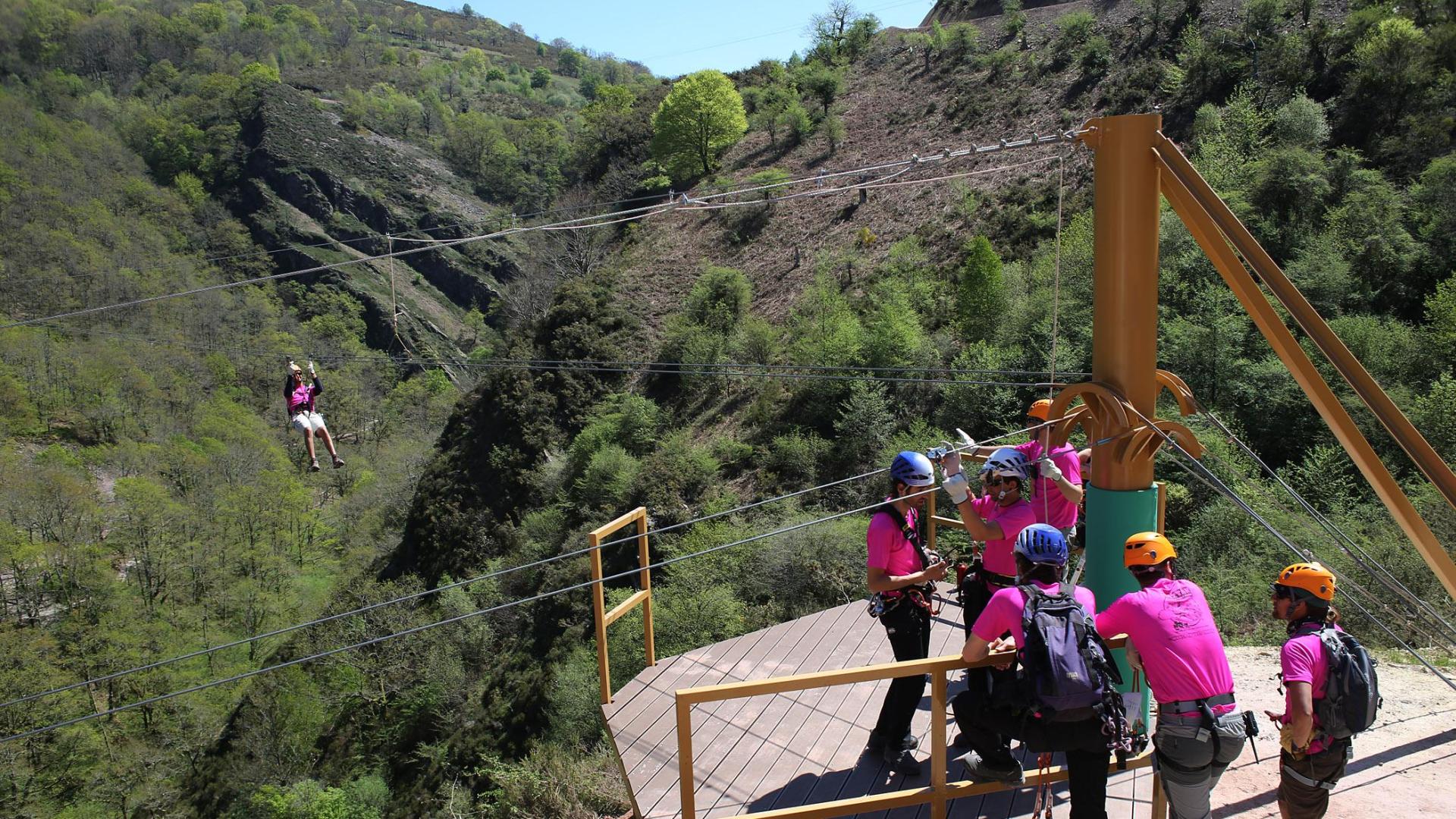 Un grupo de personas aguarda en una plataforma del parque de aventuras para lanzarse por unas tirolinas.