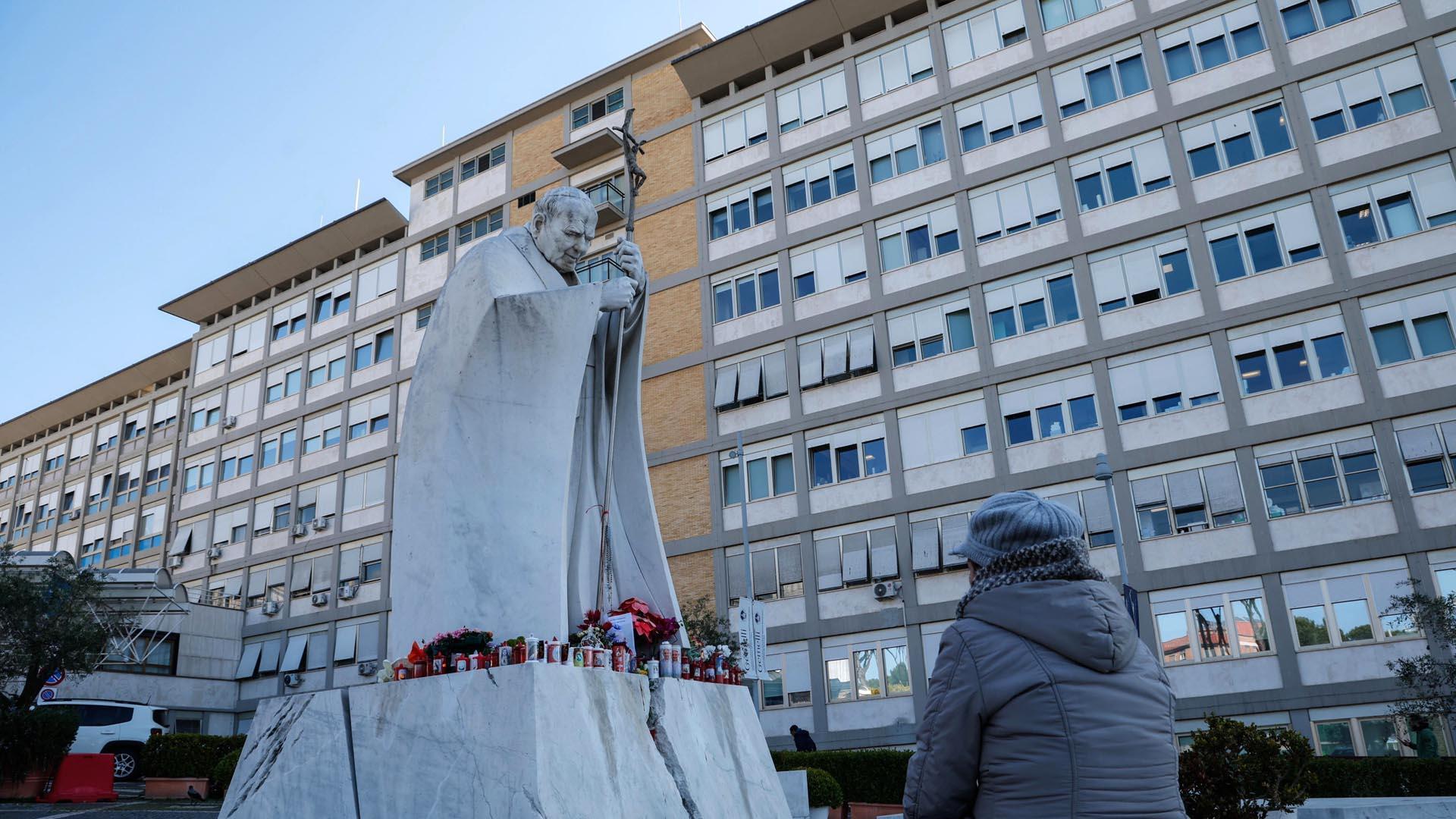 Una persona reza ante el estatua de Juan Pablo II, en el exterior del hospital Gemelli de Roma