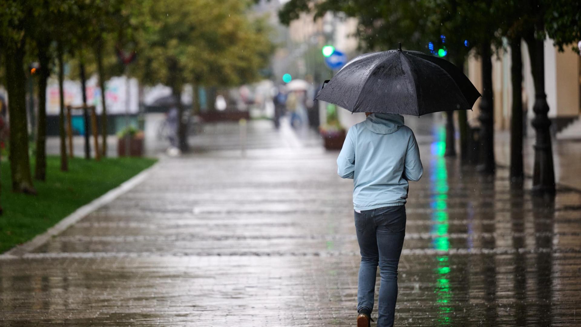 Una persona camina bajo la lluvia por Pampplona