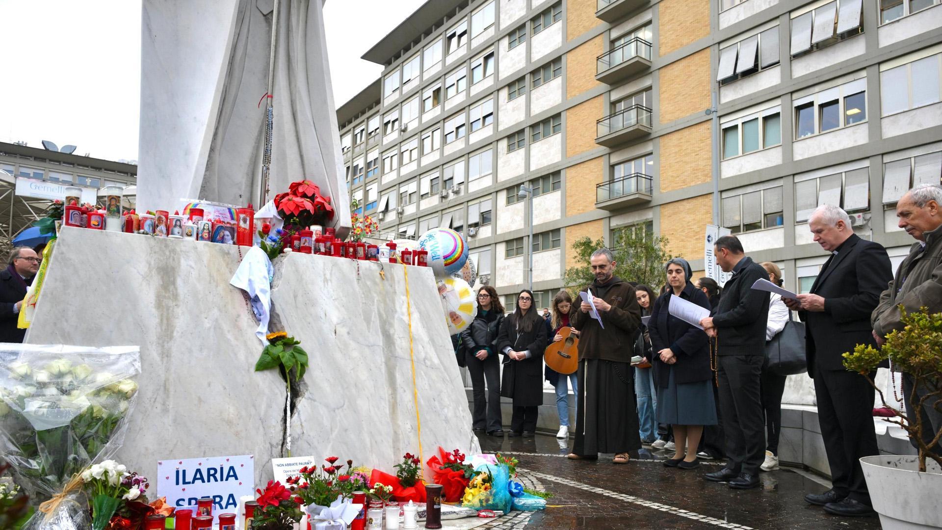 Rezos y flores por el papa junto a la estatua de Juan Pablo II en el exterior del hospital Gemelli de Roma