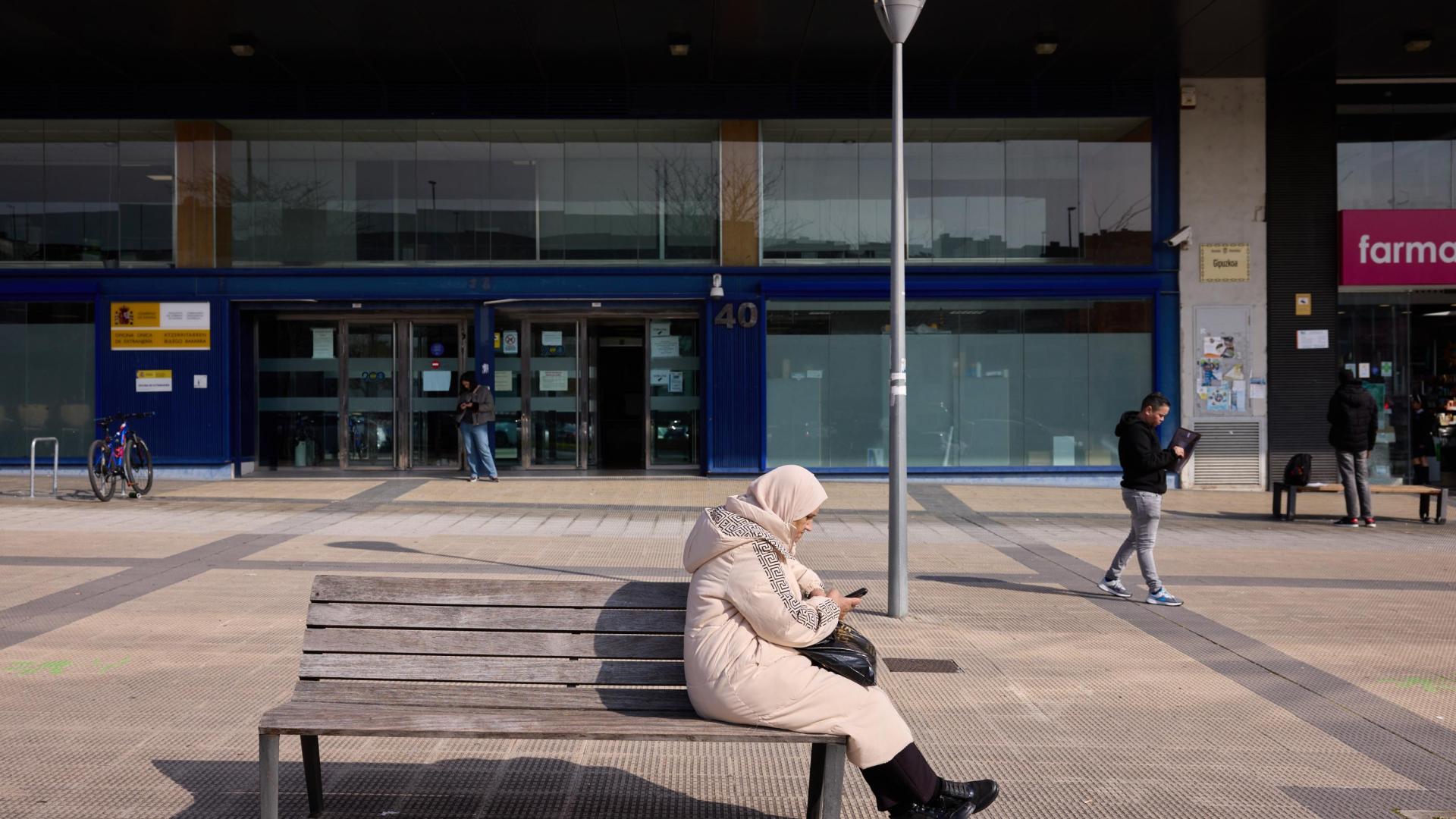 Una mujer consulta su móvil en las inmediaciones de la oficina de Extranjería de Pamplona