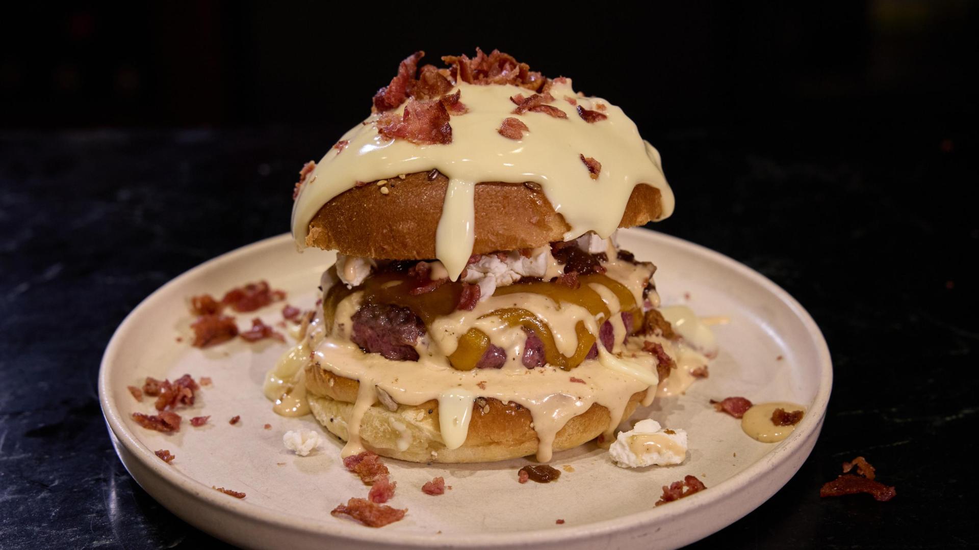 creación de los clientes y seguidores de Gastro Okei Errialde, Foodie Team. Carne con doble de queso cheddar, salsa Romero’s House, cebolla caramelizada, queso rulo de cabra, bacon crujiente y más salsa por encima del pan (opcional).