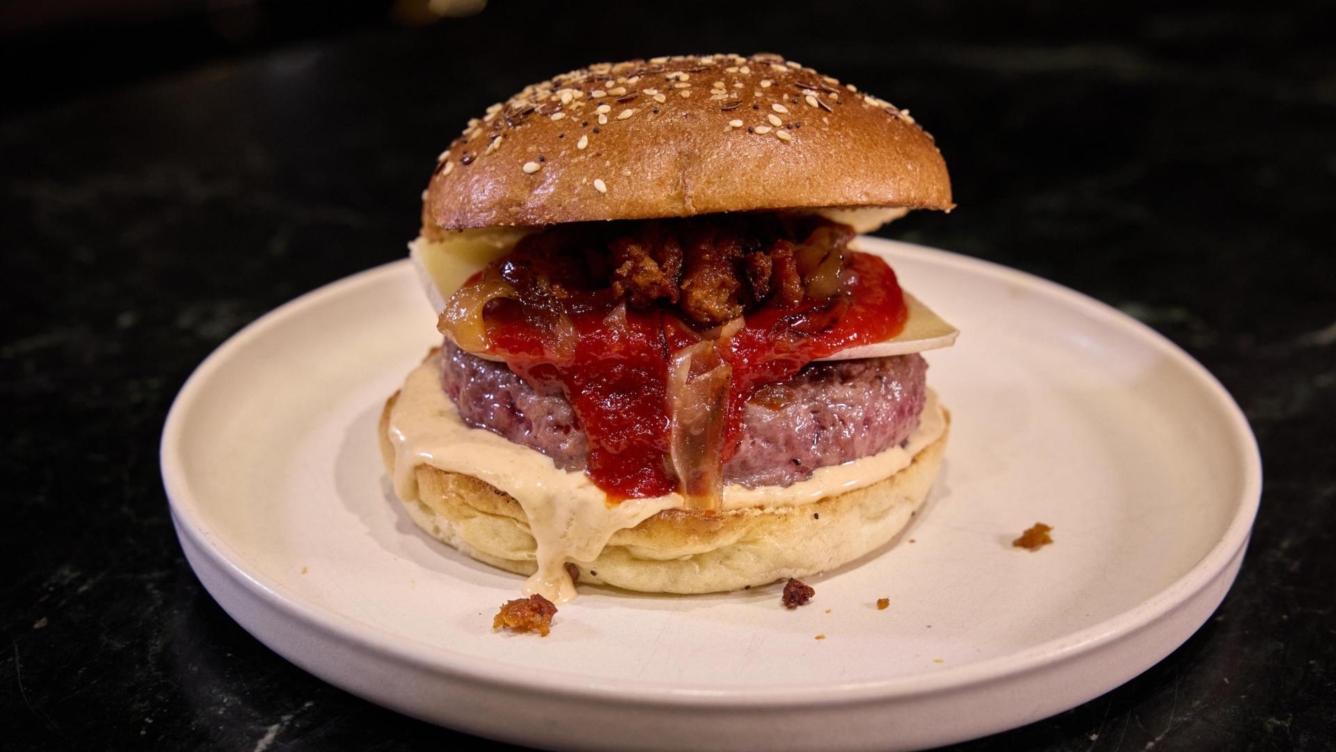 Obra de los creadores de contenido gastronómico de Navarra, Foodie Team. Carne con queso del Roncal, mayonesa trufada, mermelada de pimientos piquillos, cebolla flambeada con pacharán y chistorra crujiente.