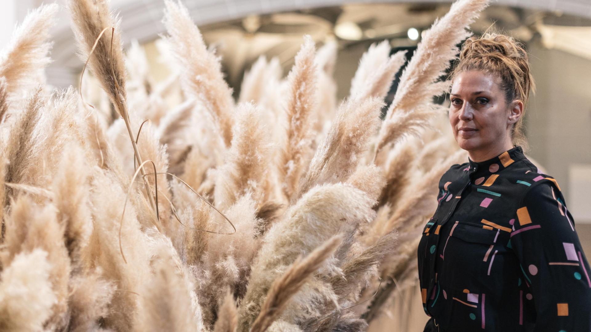 La artista Monika Aranda rodeada de plumeros de la Pampa