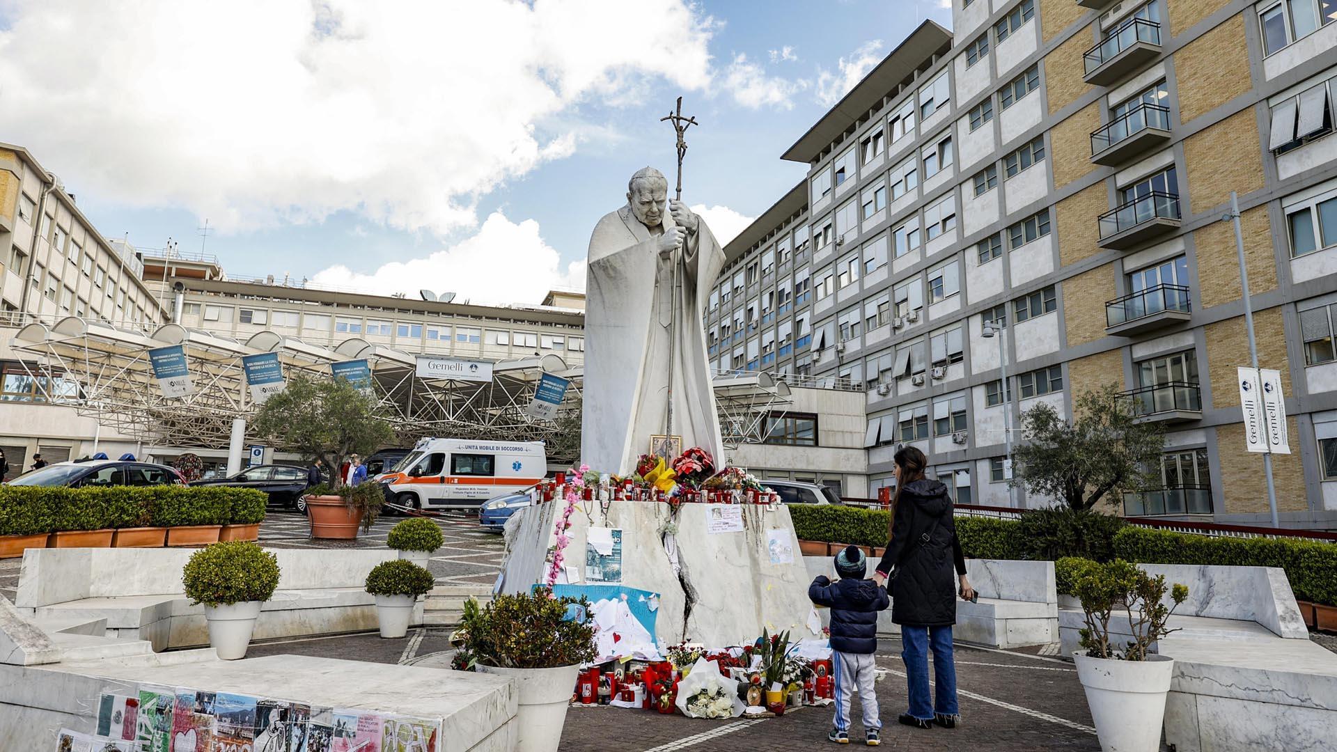 Una mujer y un niño, ante la estatua de Juan Pablo II en el exterior del hospital Gemelli de roma
