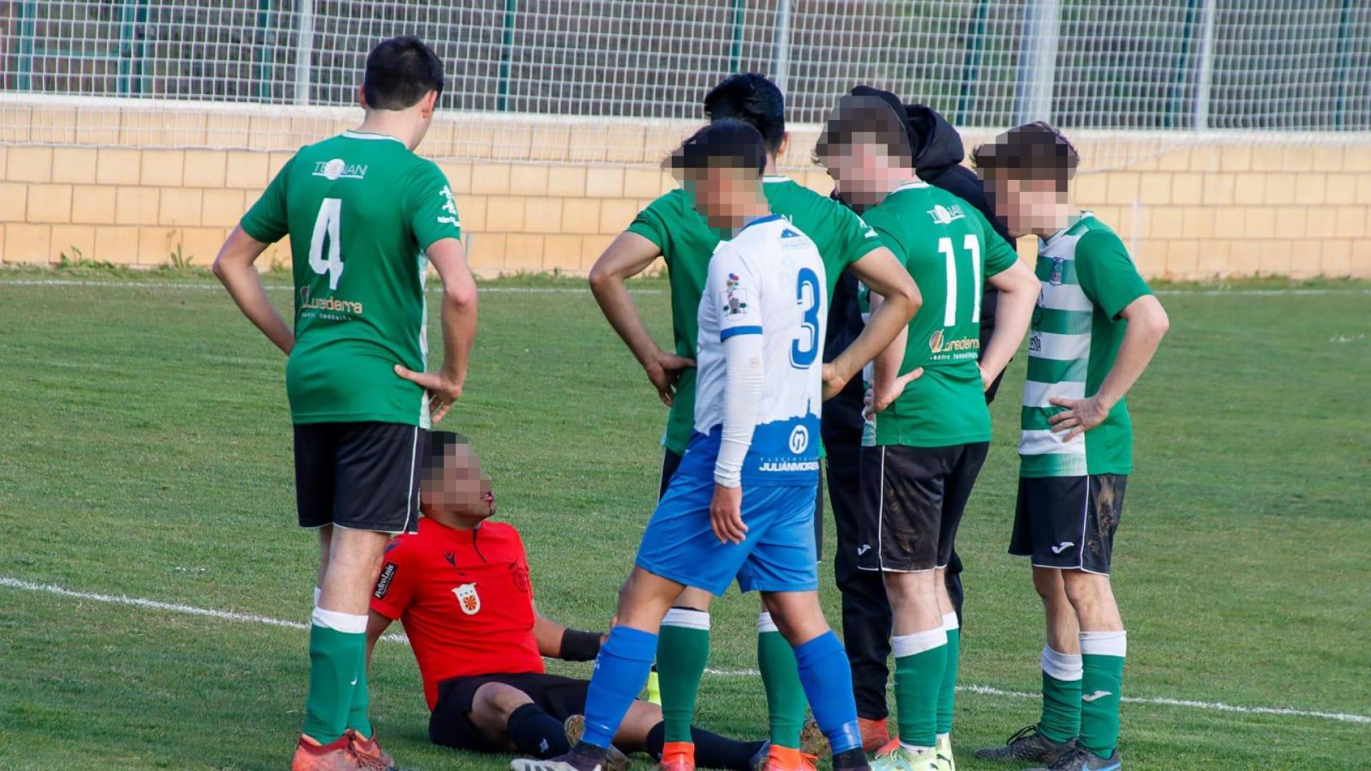 El árbitro, en el suelo con una herida en el labio, junto a jugadores de ambos equipos que se interesan por él