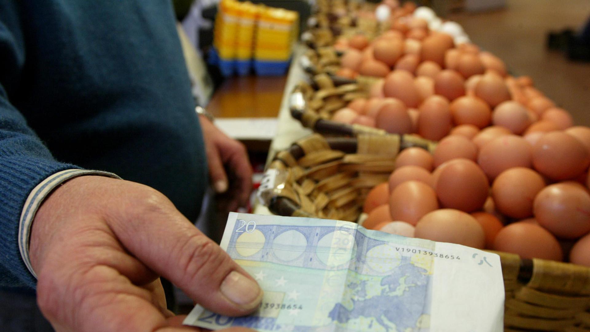 Una persona usa un billete de 20 euros para comprar huevos