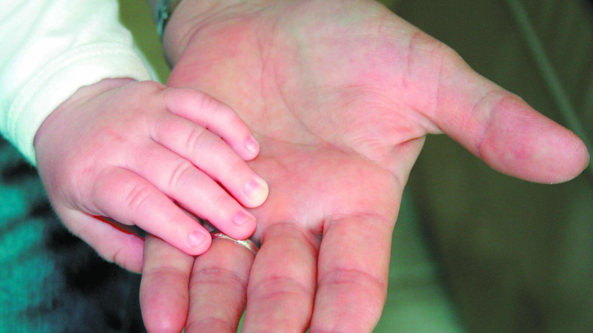 Un niño pone su mano sobre la de su padre