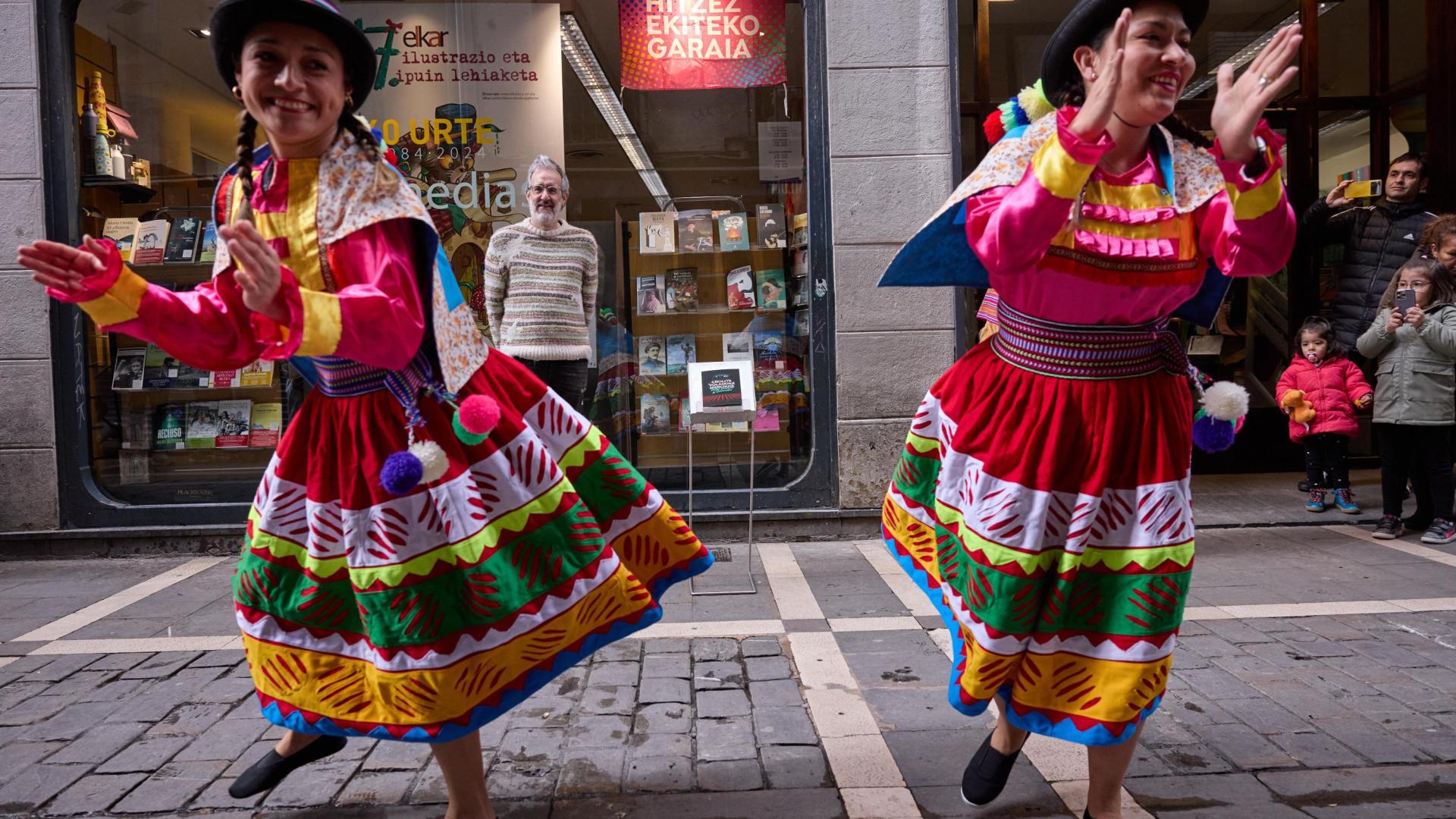 Patxi Irurzun, al fondo, observa a las dos cholitas que bailaron en la presentación de su última novela, Cholita voladora marciana, en la librería Elkar Comedias de Pamplona