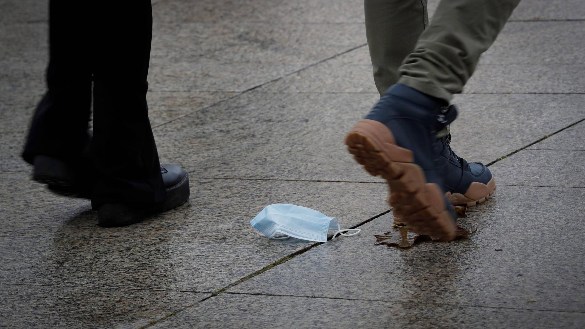 Un hombre camina por Pamplona con una mascarilla tirada en el suelo