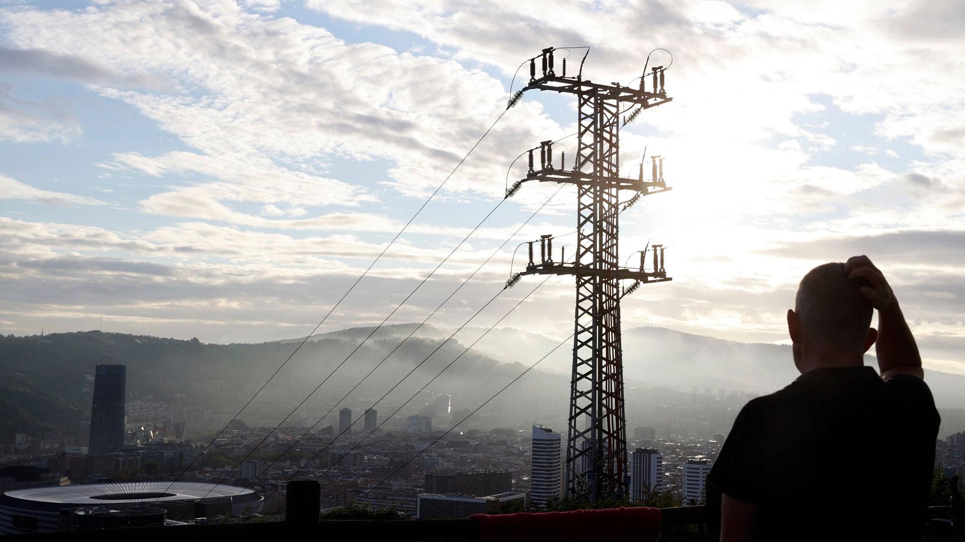 Una persona observa el cableado con el que Red Eléctrica transporta la energía sobre la ciudad de Bilbao