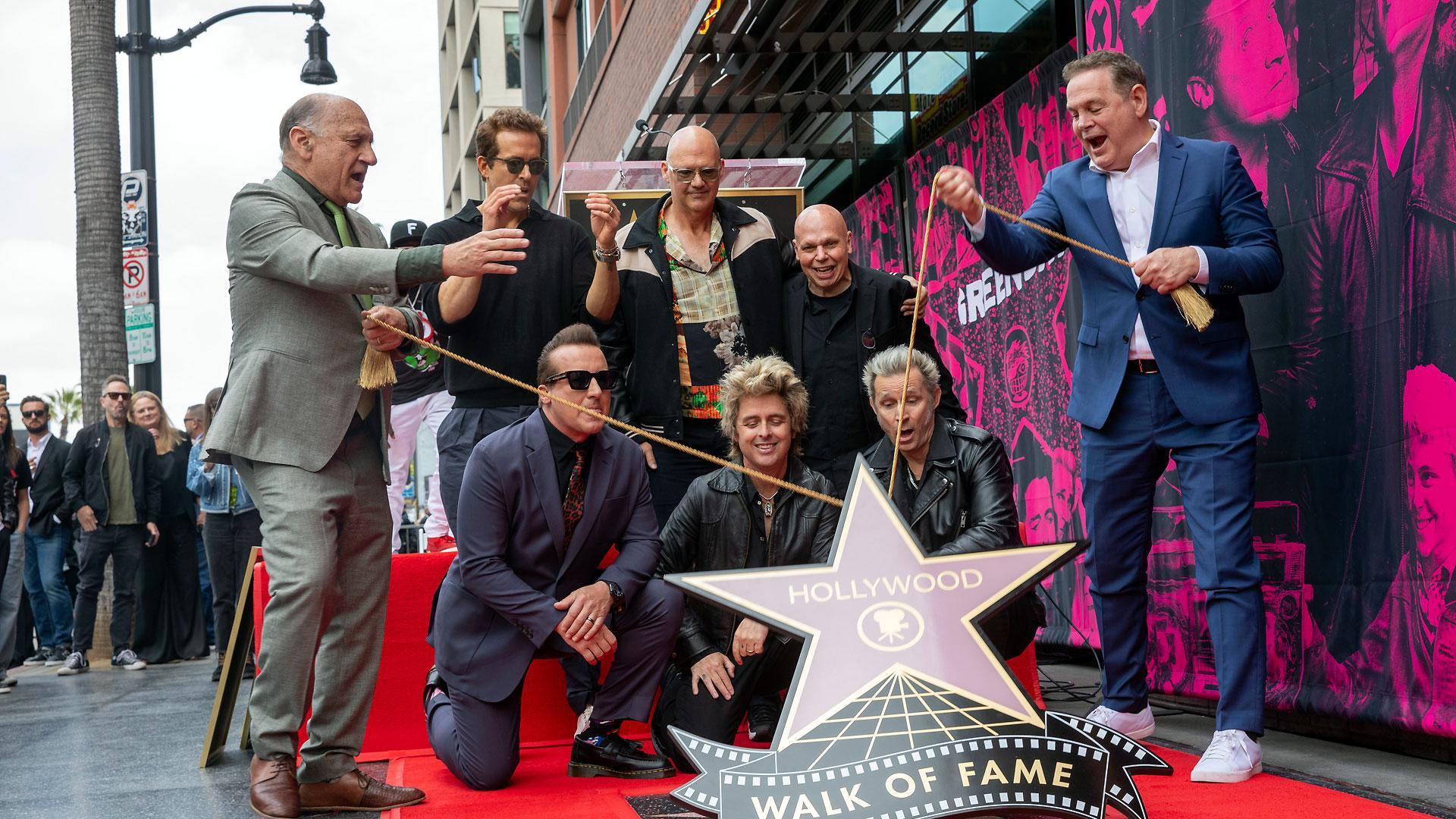 Los miembros de Green Day Tre Cool, Billie Joe Armstrong y Mike Dirnt observan cómo se revela su estrella durante la ceremonia en el Paseo de la Fama de Hollywood en honor a la banda