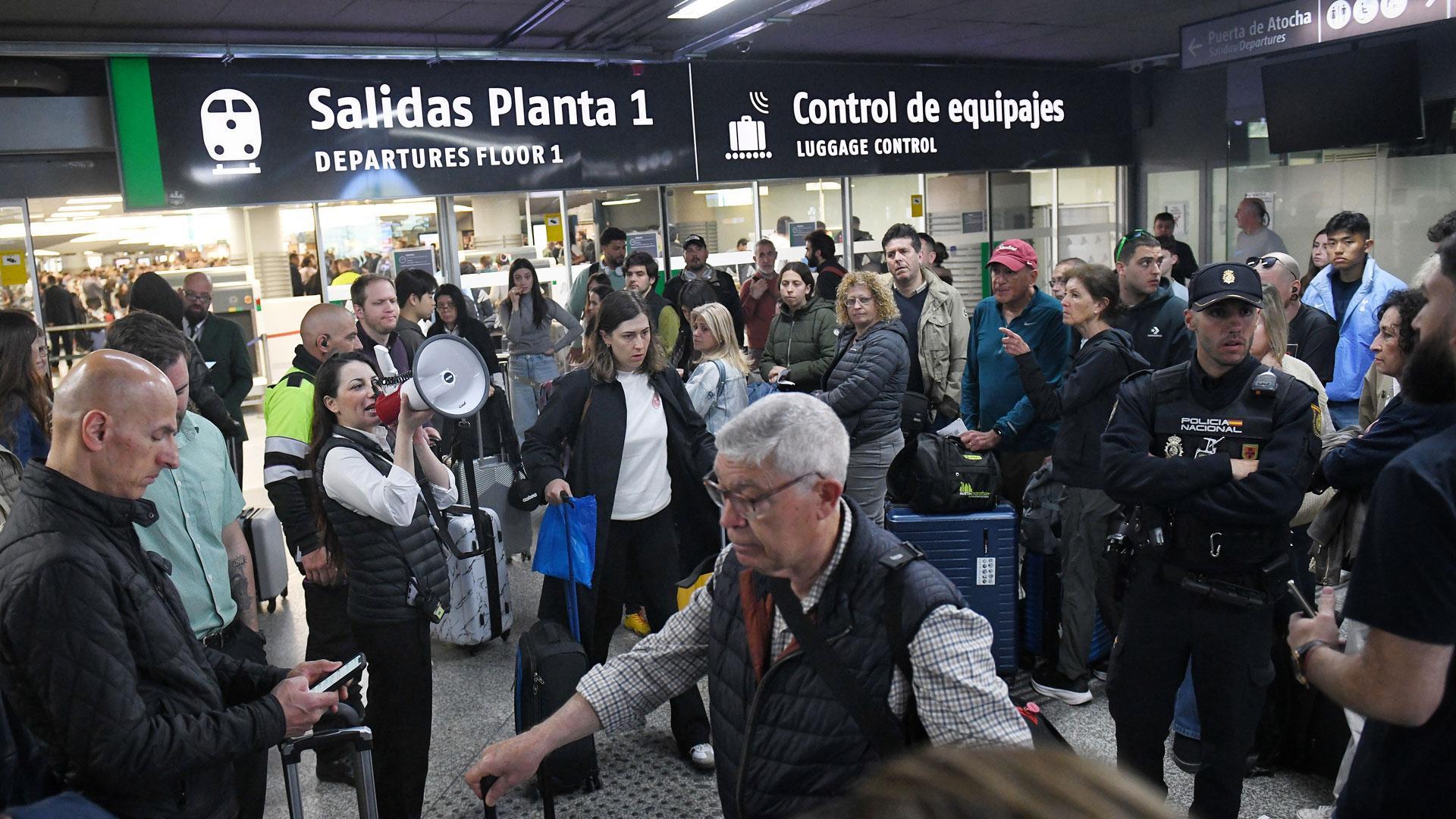 Una trabajadora con un megáfono en la estación de Atocha-Almudena Grandes, tras los retrasos en los trenes AVE