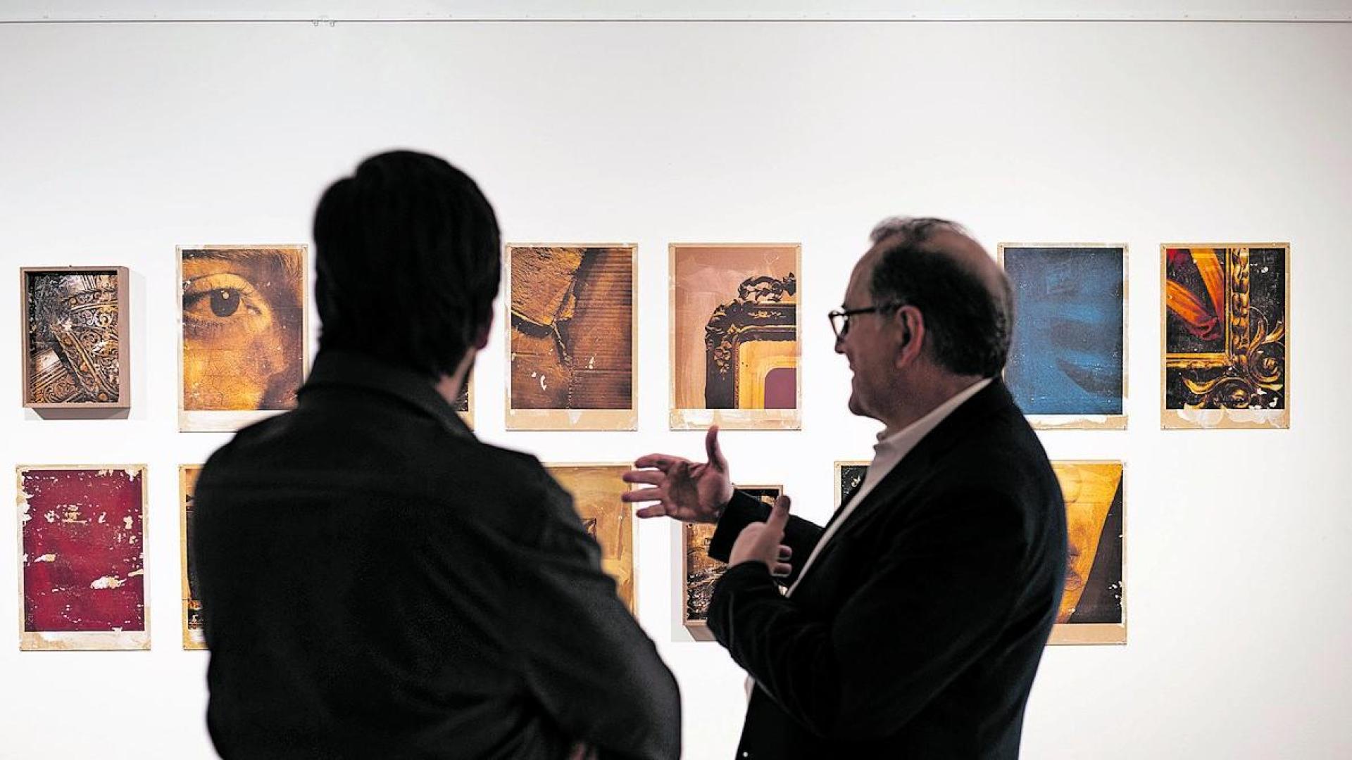 El artista de espaldas y un visitante observan la exposición en la Casa de Cultura de Zizur Mayor